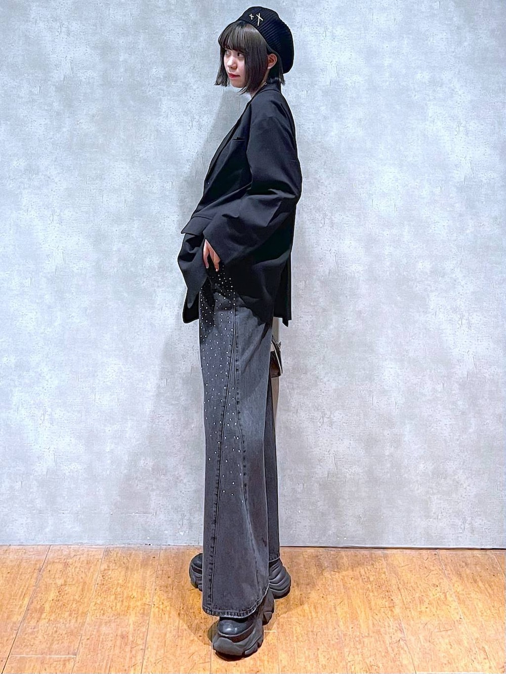 ブラック系のスニーカー、ブラック系のデニムパンツ、ブラック系のショルダーバッグを着用したレディースの秋コーディネートの4枚目の写真