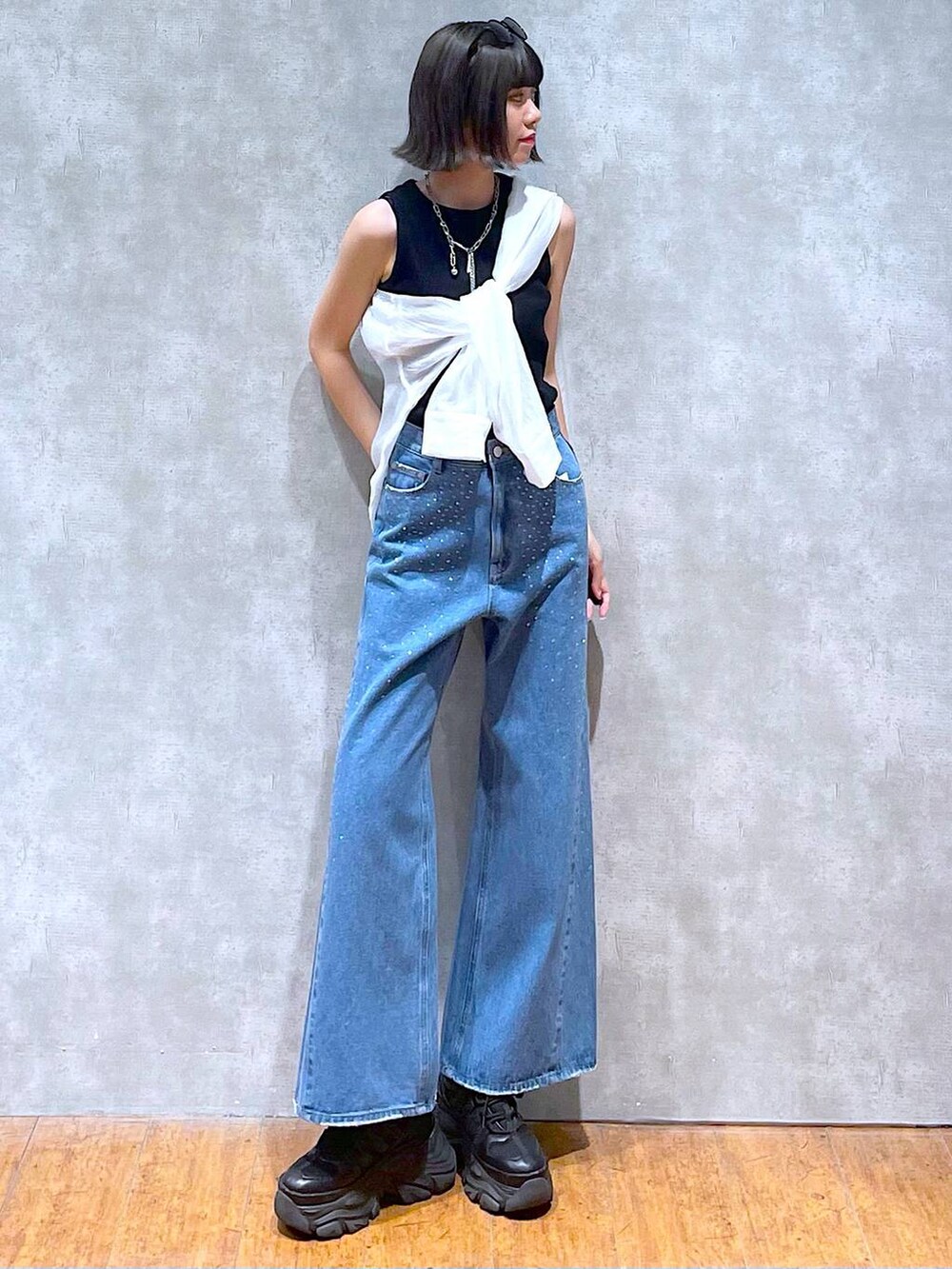 ブラック系のスニーカー、ブラック系のタンクトップ、ブルー系のデニムパンツを着用したレディースの夏コーディネートの2枚目の写真