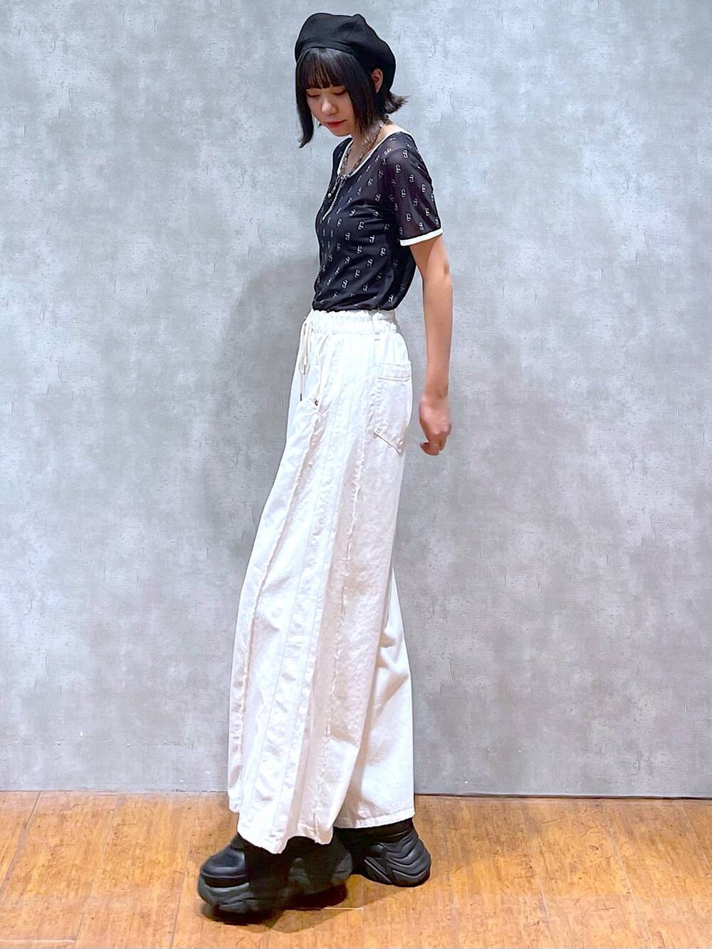 ブラック系のスニーカー、ブラック系のキャミソール、ホワイト系のデニムパンツを着用したレディースの夏コーディネートの4枚目の写真