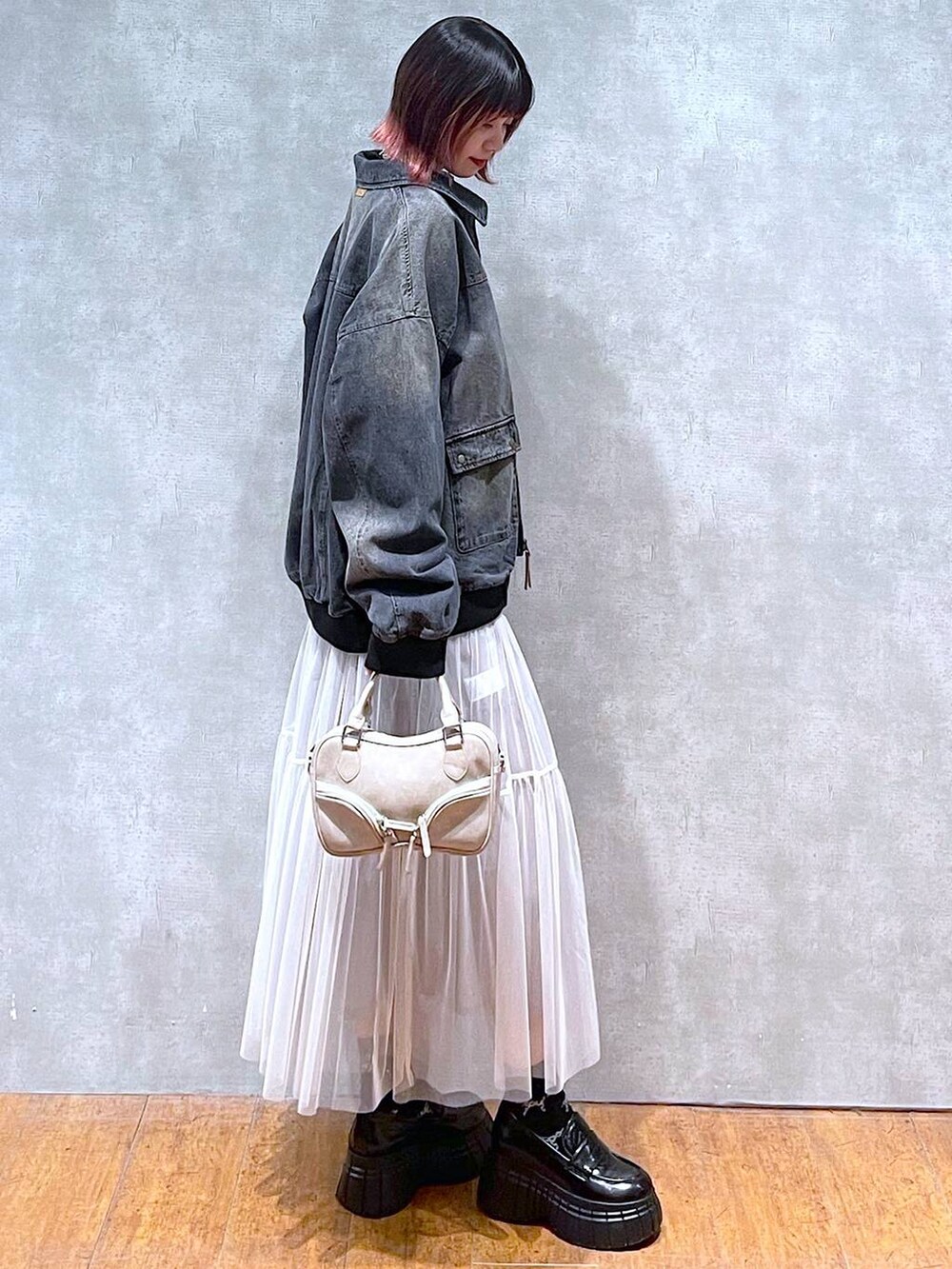 ブラック系のニット/セーター、ブラック系のデニムジャケット、ホワイト系のスカートを着用したレディースの冬コーディネートの6枚目の写真