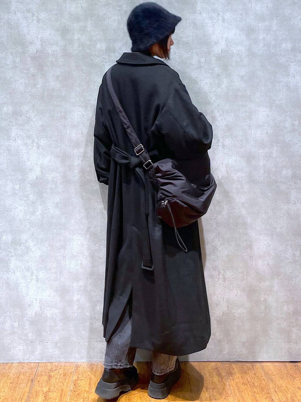 ブラック系のブーツ、ブラック系のチェスターコート、ブラック系のデニムパンツを着用したレディースの冬コーディネートの5枚目の写真