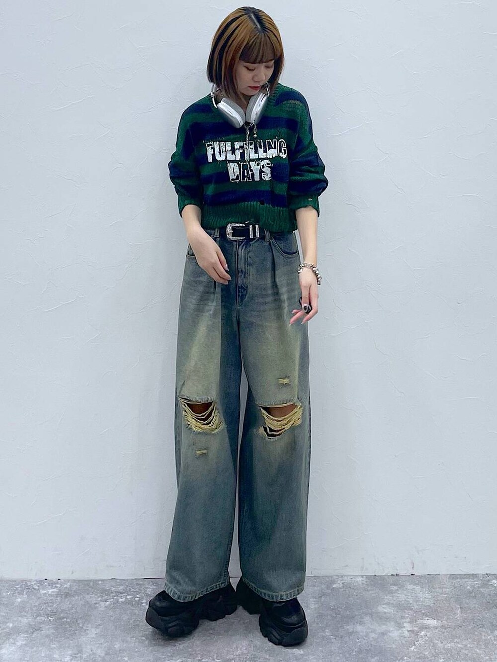 ブラック系のスニーカー、ブルー系のデニムパンツ、グリーン系のニット/セーターを着用したレディースの秋コーディネートの6枚目の写真