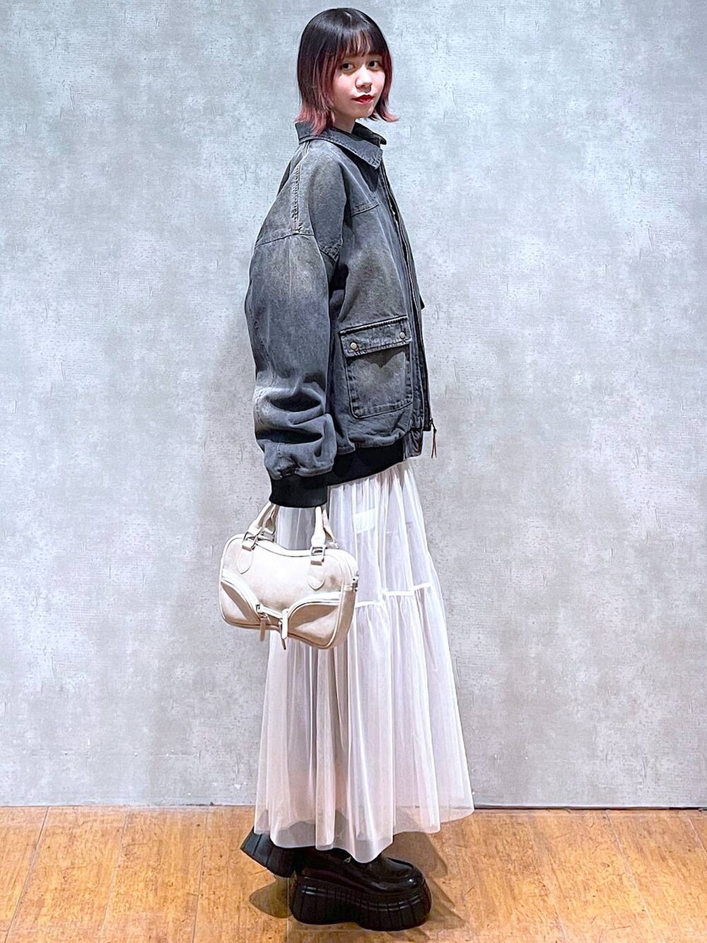 ブラック系のニット/セーター、ブラック系のデニムジャケット、ホワイト系のスカートを着用したレディースの冬コーディネートの5枚目の写真