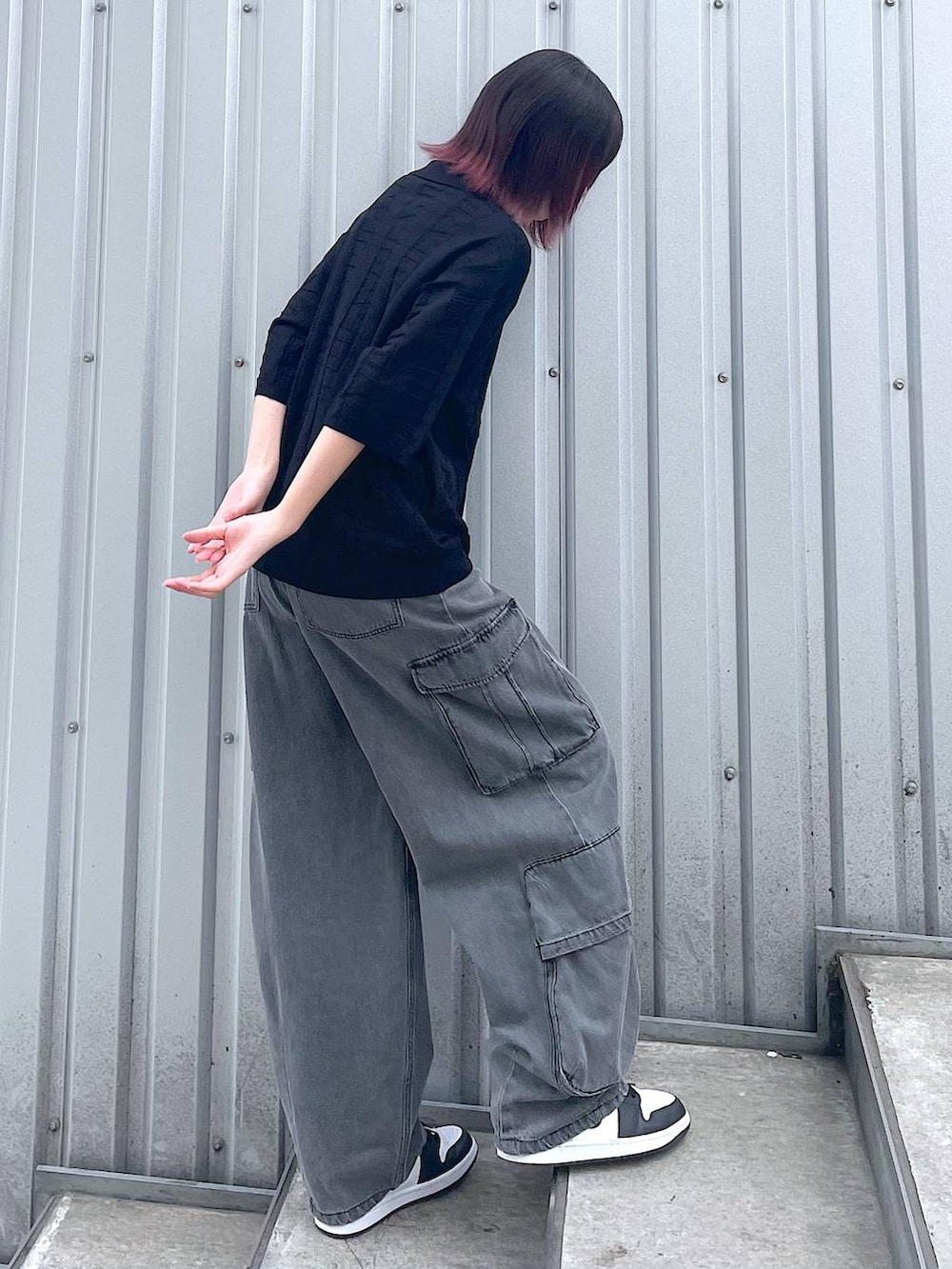 ブラック系のニット/セーター、ブラック系のデニムパンツ、ブラック系のベルトを着用したレディースの春コーディネートの4枚目の写真