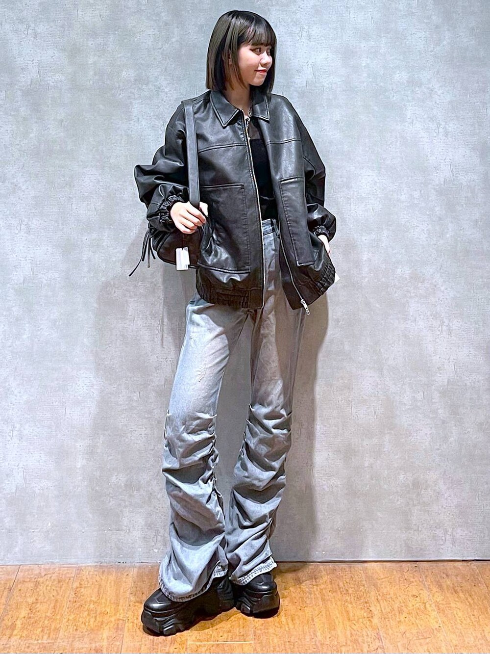 ブラック系のスニーカー、ブラック系のショルダーバッグ、ブルー系のデニムパンツを着用したレディースの秋コーディネートの6枚目の写真