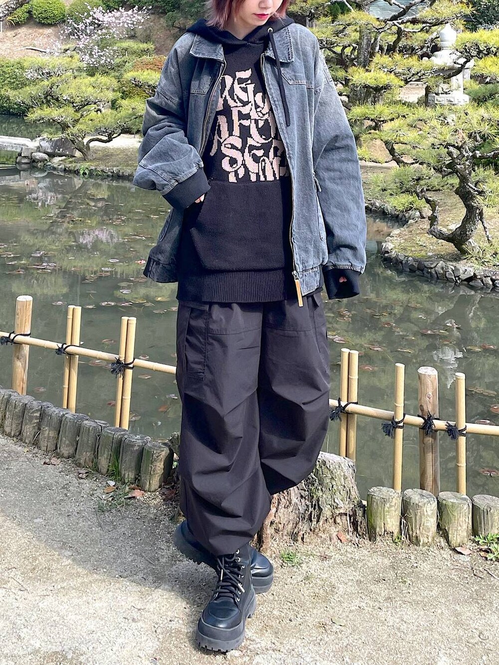 ブラック系のデニムジャケット、ブラック系のブーツ、ブラック系のスラックスを着用したレディースの春コーディネートの3枚目の写真