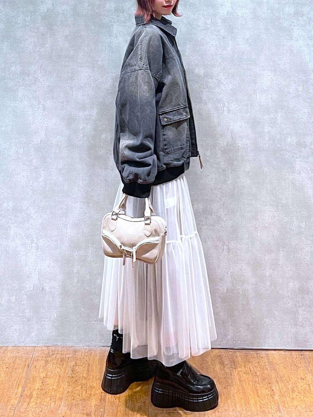 ブラック系のニット/セーター、ブラック系のデニムジャケット、ホワイト系のスカートを着用したレディースの冬コーディネートの7枚目の写真