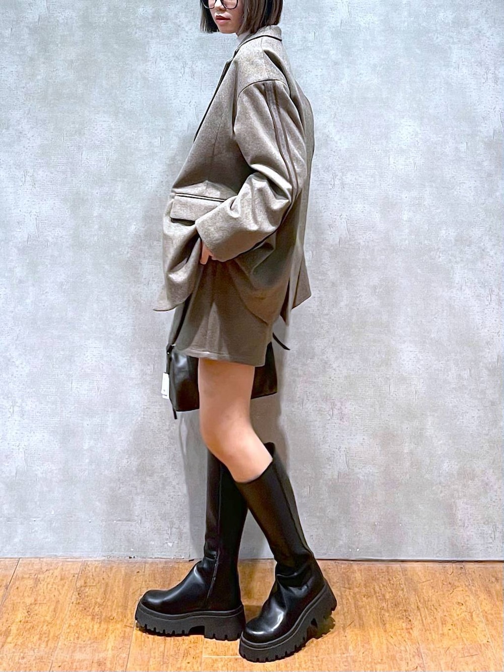 ブラック系のショルダーバッグ、ホワイト系のニット/セーター、ブラック系のブーツを着用したレディースの秋コーディネートの4枚目の写真