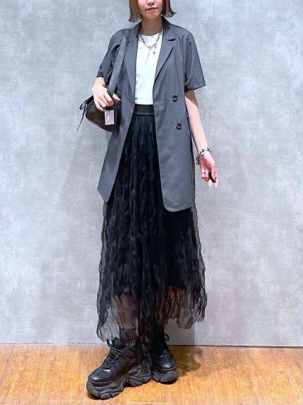 ブラック系のスニーカー、グレー系のテーラードジャケット、ホワイト系のTシャツ/カットソーを着用したレディースの夏コーディネートの6枚目の写真