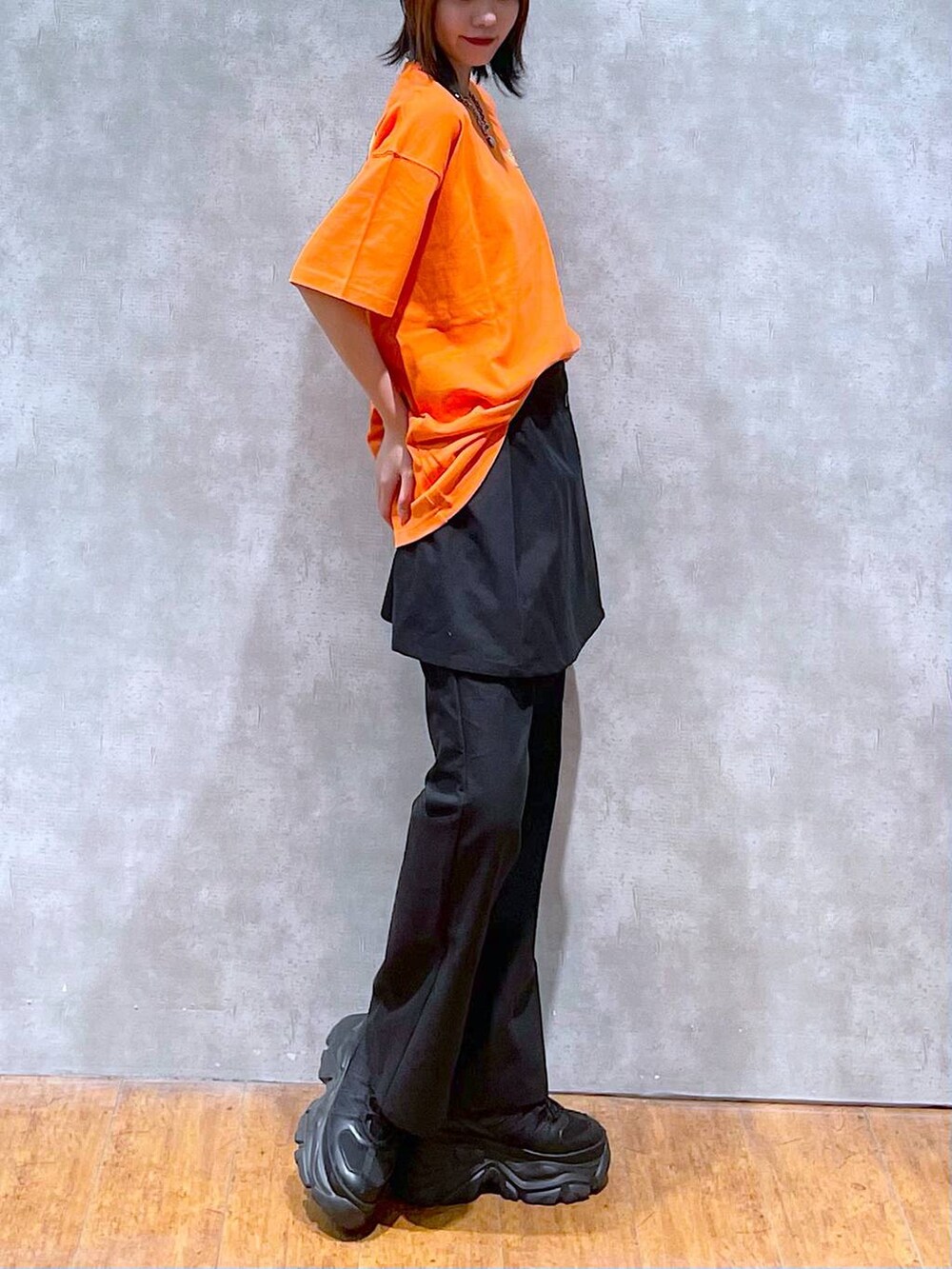 ブラック系のスニーカー、オレンジ系のTシャツ/カットソー、ブラック系のチノパンツを着用したレディースの夏コーディネートの4枚目の写真