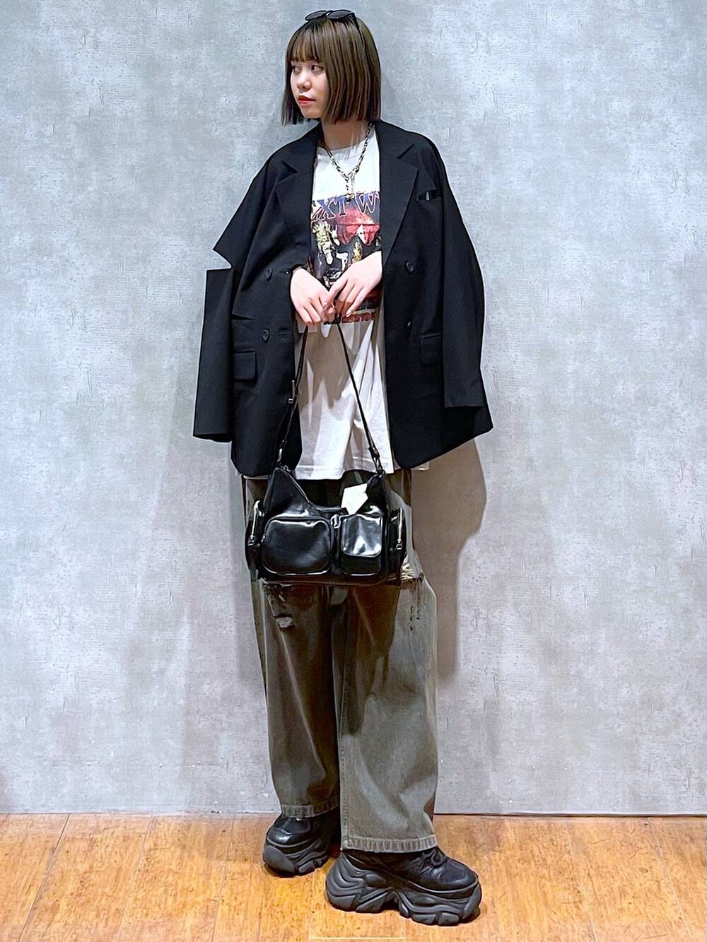 ブラック系のスニーカー、ベージュ系のTシャツ/カットソー、ブラック系のデニムパンツを着用したレディースの秋コーディネートの2枚目の写真