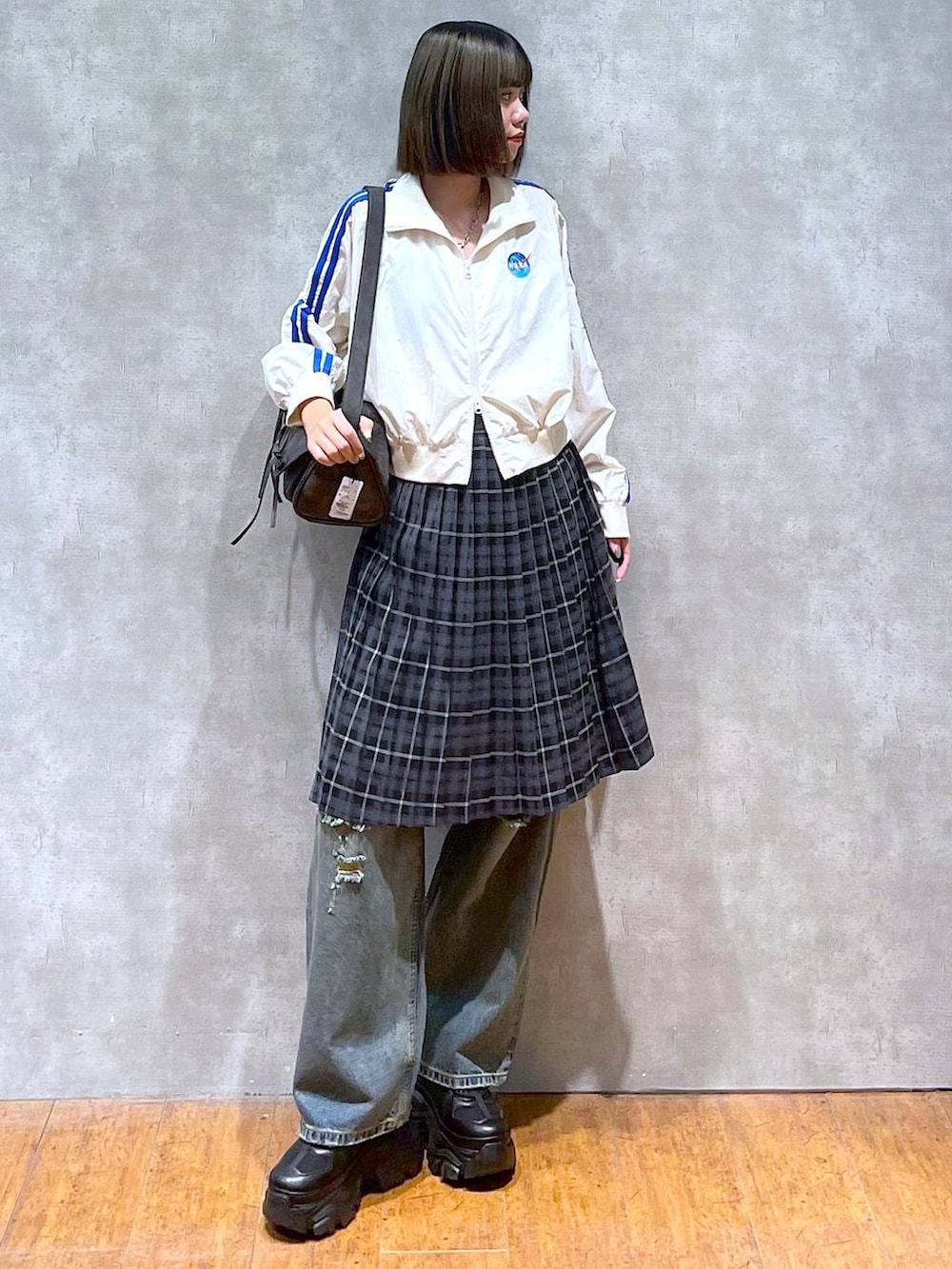 ブラック系のスニーカー、ブラック系のショルダーバッグ、ブルー系のデニムパンツを着用したレディースの秋コーディネートの8枚目の写真