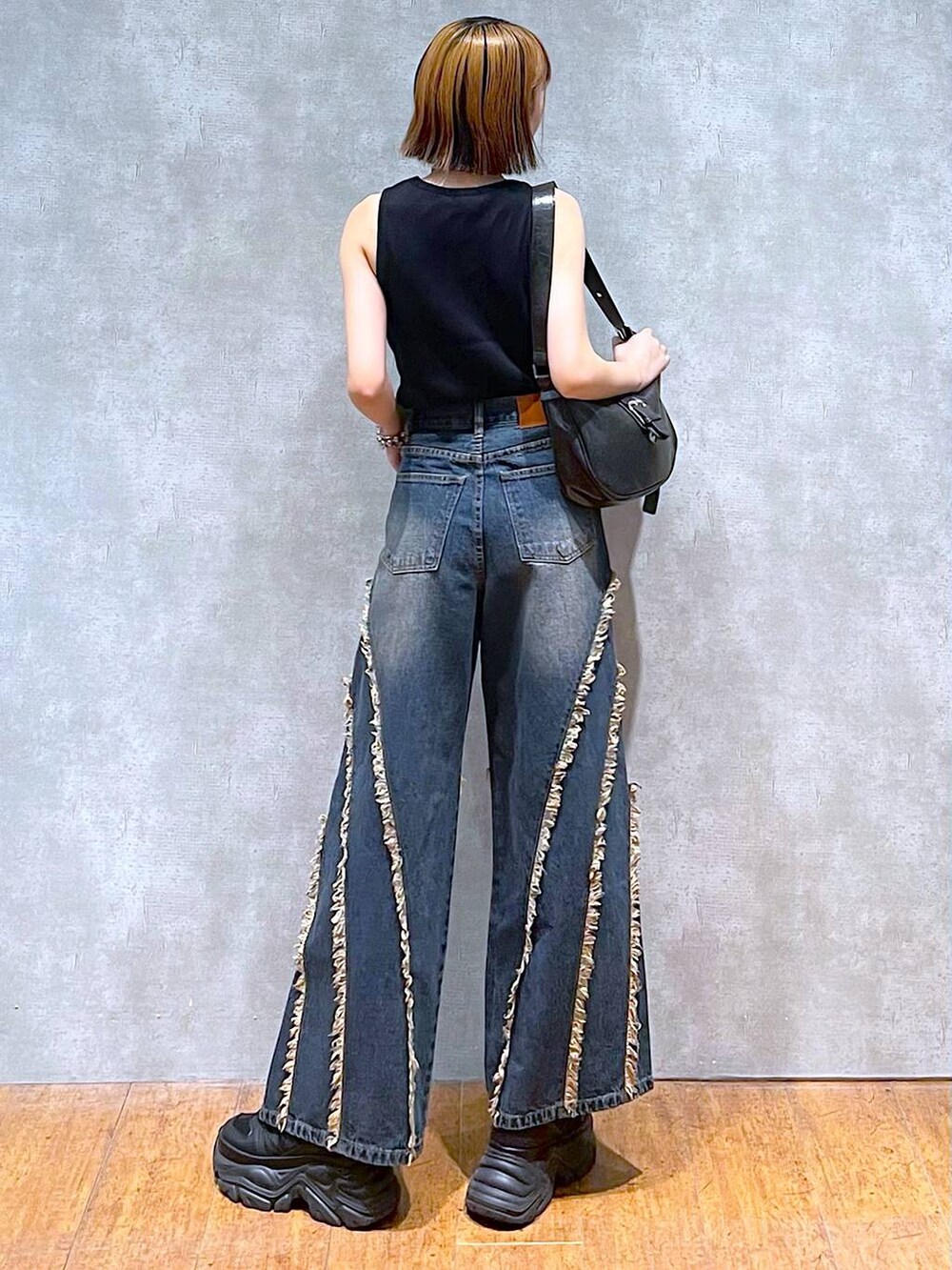 ブラック系のスニーカー、ブラック系のタンクトップ、ブルー系のデニムパンツを着用したレディースの夏コーディネートの5枚目の写真