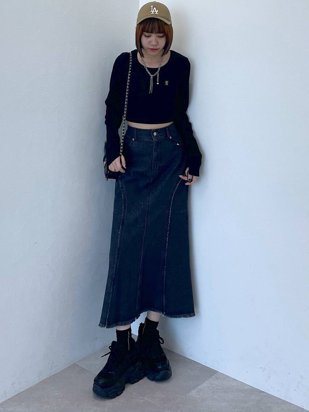 ブラック系のスニーカー、ブラック系のデニムスカート、ブラック系のTシャツ/カットソーを着用したレディースの秋コーディネートの6枚目の写真