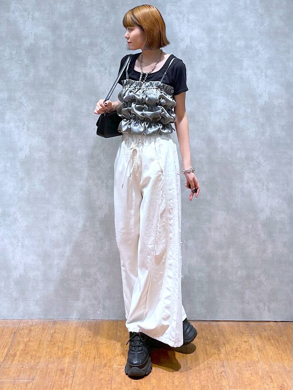 ブラック系のスニーカー、ホワイト系のデニムパンツ、ブラック系のハンドバッグを着用したレディースの夏コーディネートの4枚目の写真