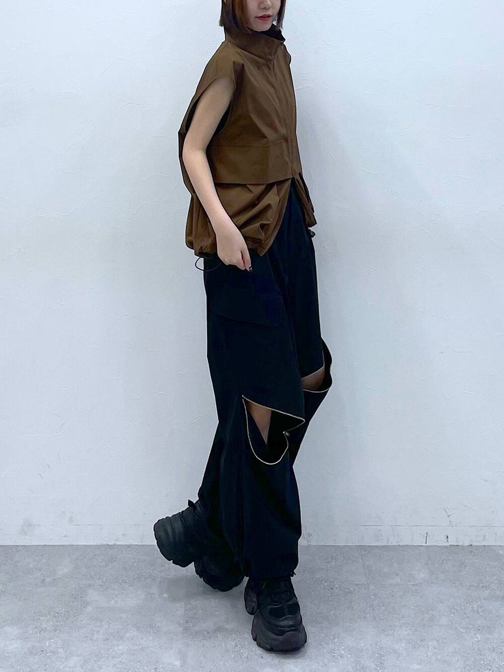 ブラック系のスニーカー、ブラック系のカーゴパンツ、ブラウン系のベストを着用したレディースの夏コーディネートの6枚目の写真