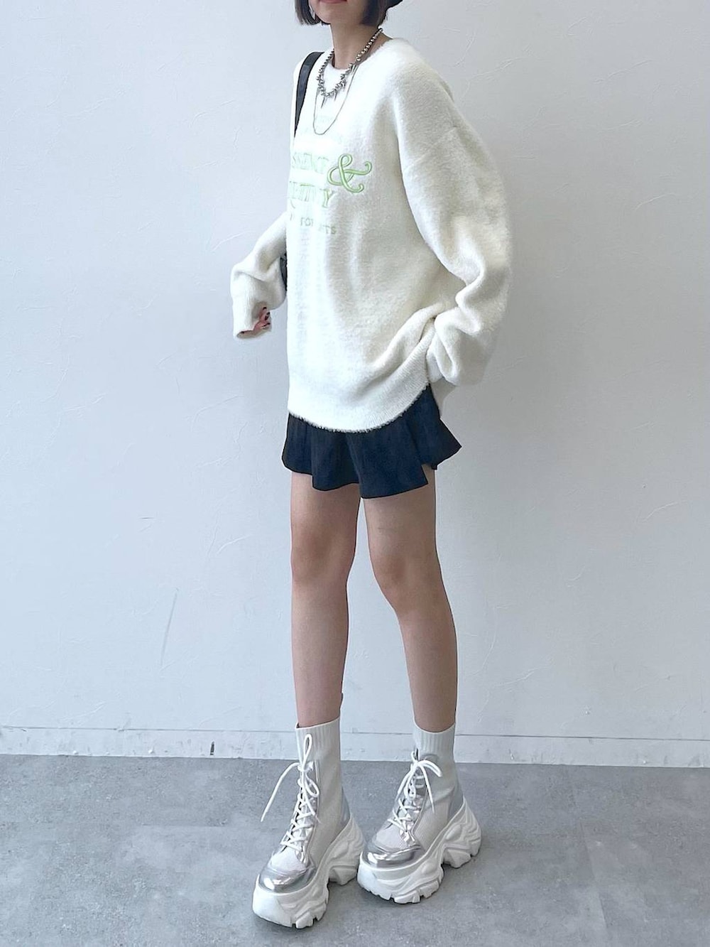 ホワイト系のブーツ、ブラック系のショルダーバッグ、ホワイト系のニット/セーターを着用したレディースの秋コーディネートの6枚目の写真