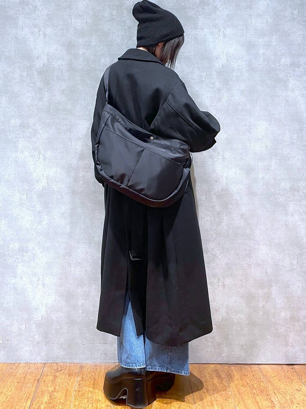 ブラック系のチェスターコート、ブルー系のデニムパンツ、イエロー系のカーディガン/ボレロを着用したレディースの冬コーディネートの2枚目の写真