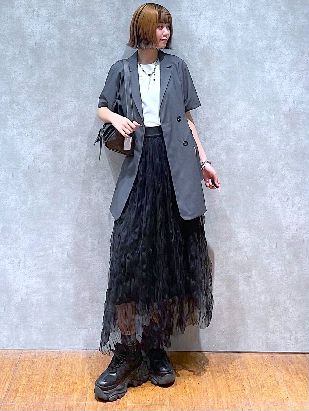 ブラック系のスニーカー、グレー系のテーラードジャケット、ホワイト系のTシャツ/カットソーを着用したレディースの夏コーディネートの2枚目の写真