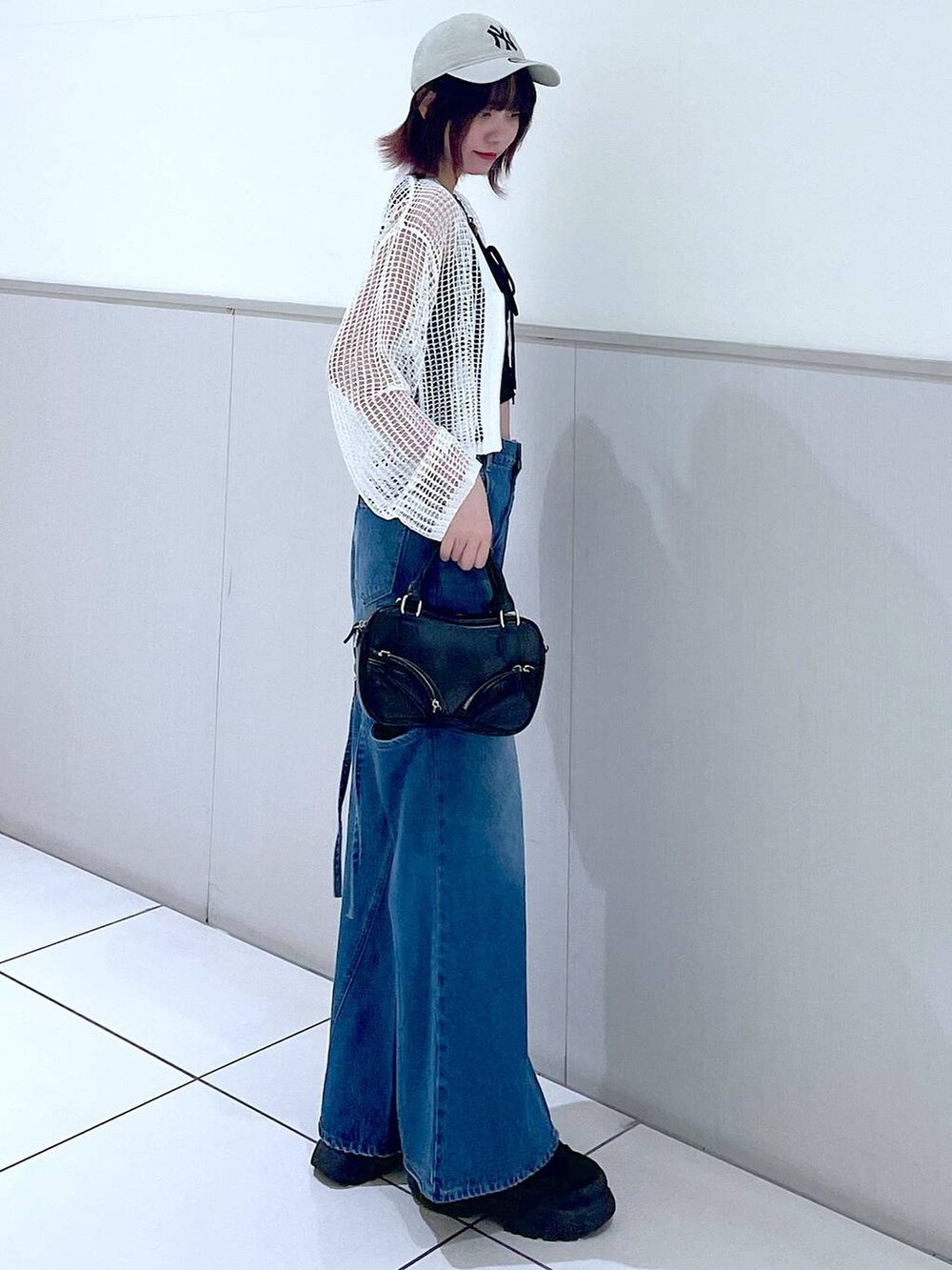 ホワイト系のカーディガン/ボレロ、ブラック系のタンクトップ、ブルー系のデニムパンツを着用したレディースの春コーディネートの5枚目の写真