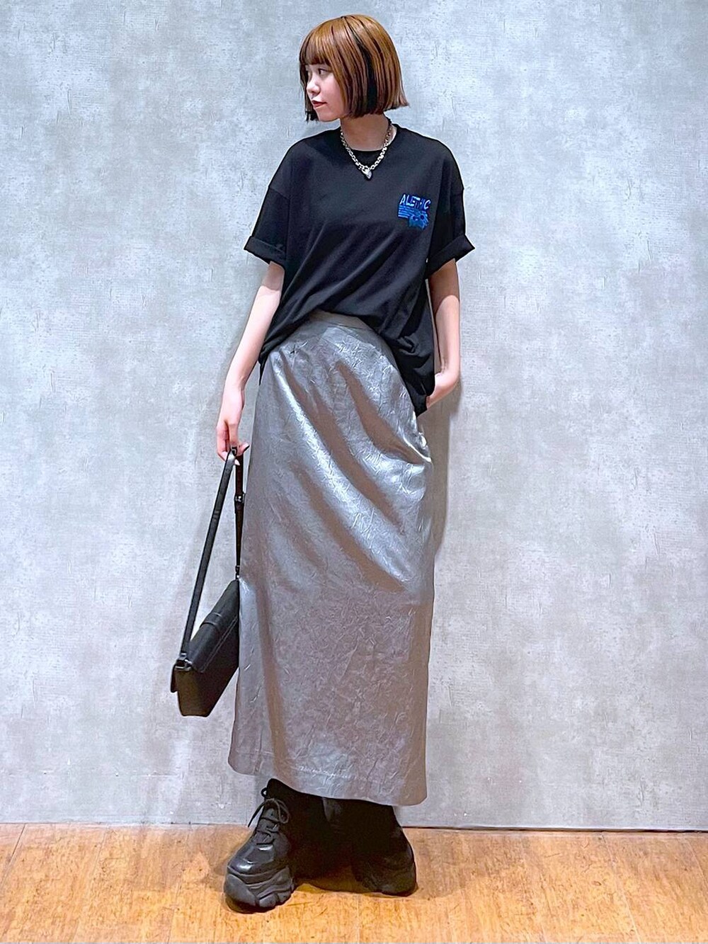 ブラック系のスニーカー、ブラック系のハンドバッグ、ブラック系のTシャツ/カットソーを着用したレディースの夏コーディネートの2枚目の写真