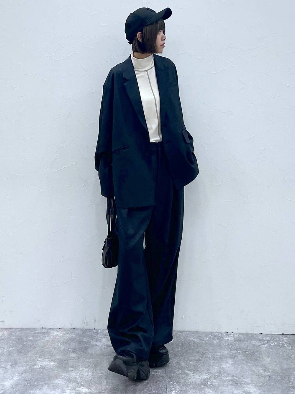 ブラック系のスニーカー、ブラック系のスラックス、ブラック系のテーラードジャケットを着用したレディースの秋コーディネートの3枚目の写真