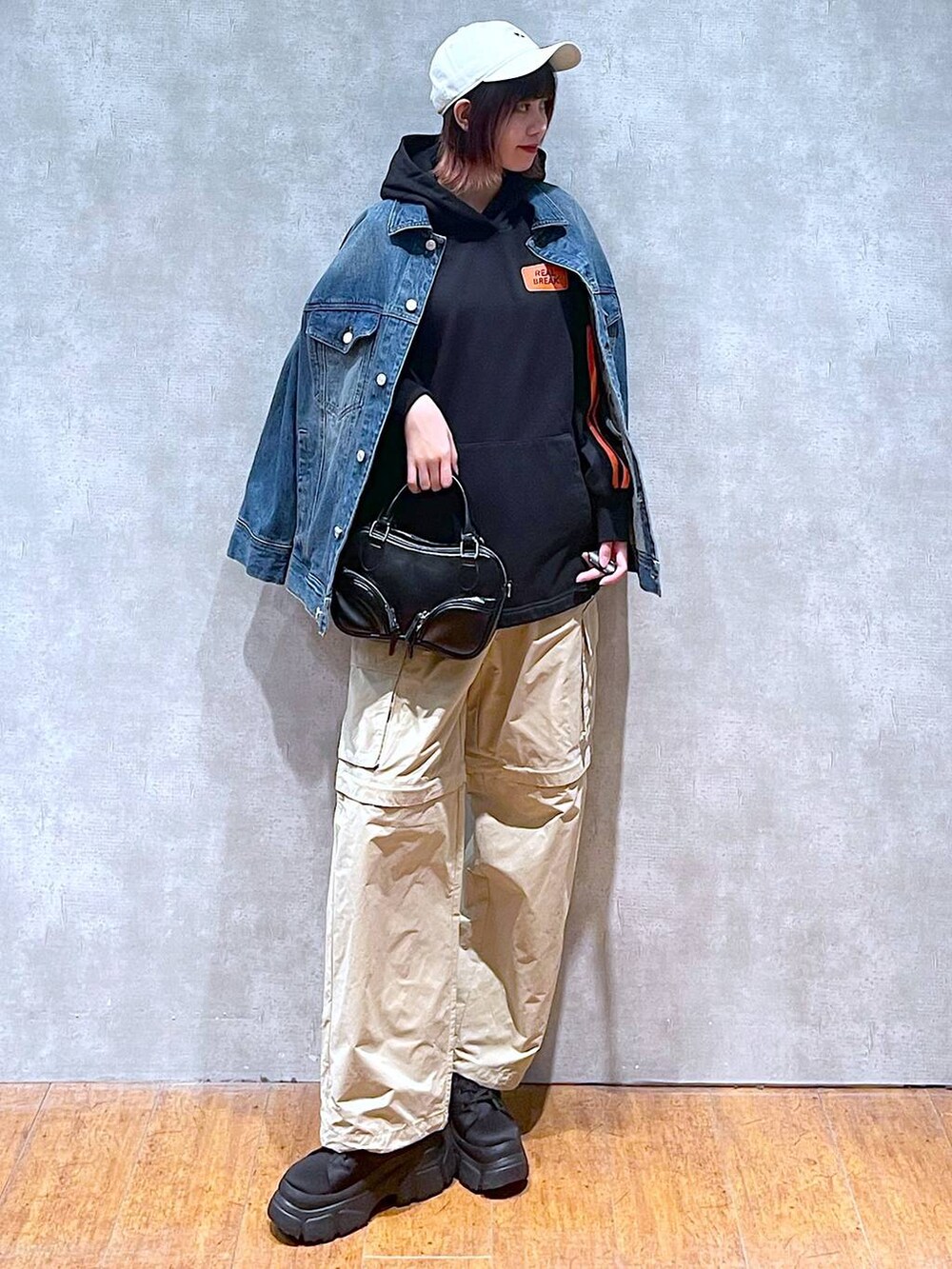 ブルー系のデニムジャケット、ベージュ系のカーゴパンツ、ブラック系のボストンバッグを着用したレディースの春コーディネートの2枚目の写真