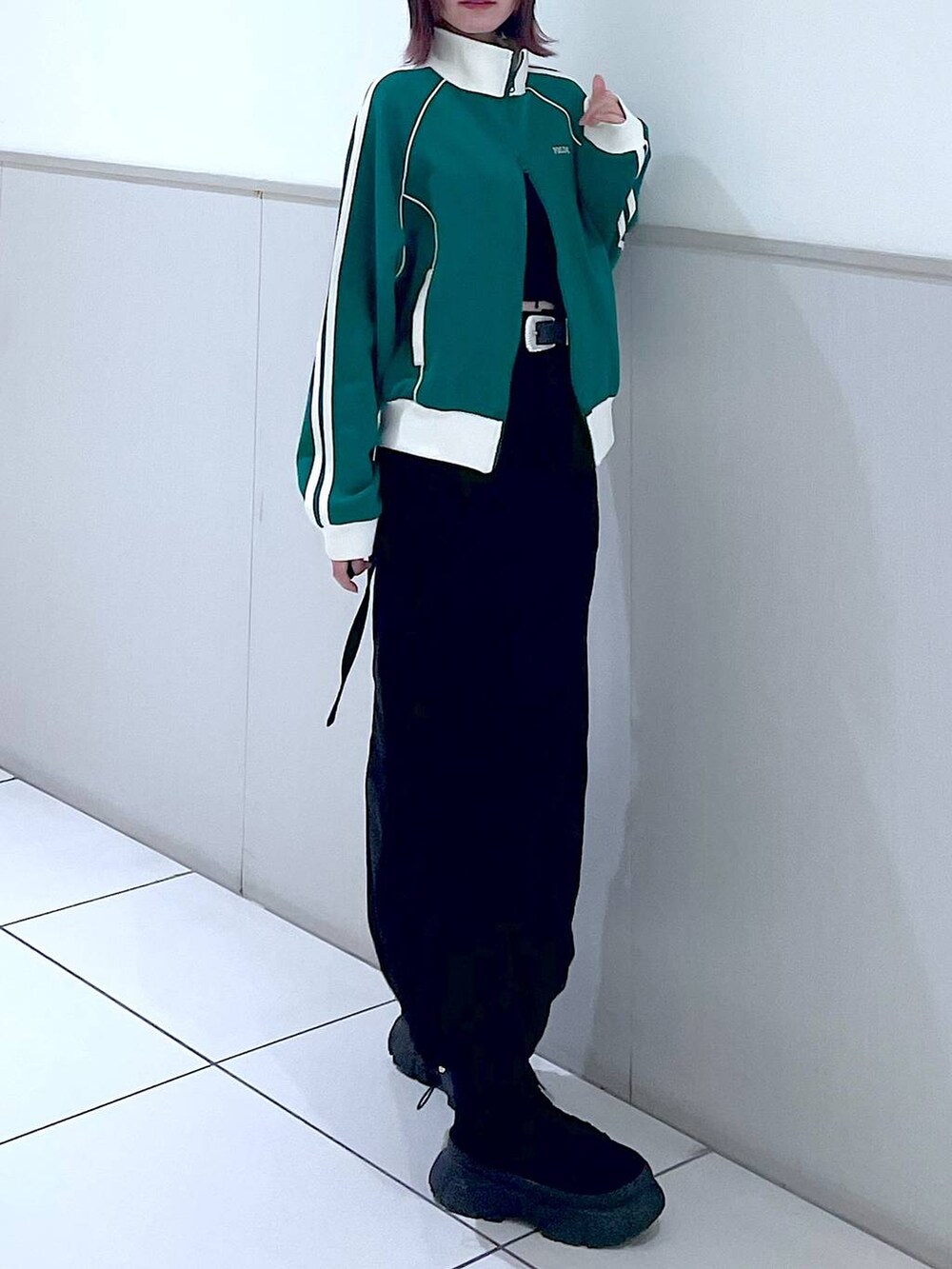 グリーン系のセットアップ、ブラック系のタンクトップ、ブラック系のブーツを着用したレディースの春コーディネートの4枚目の写真