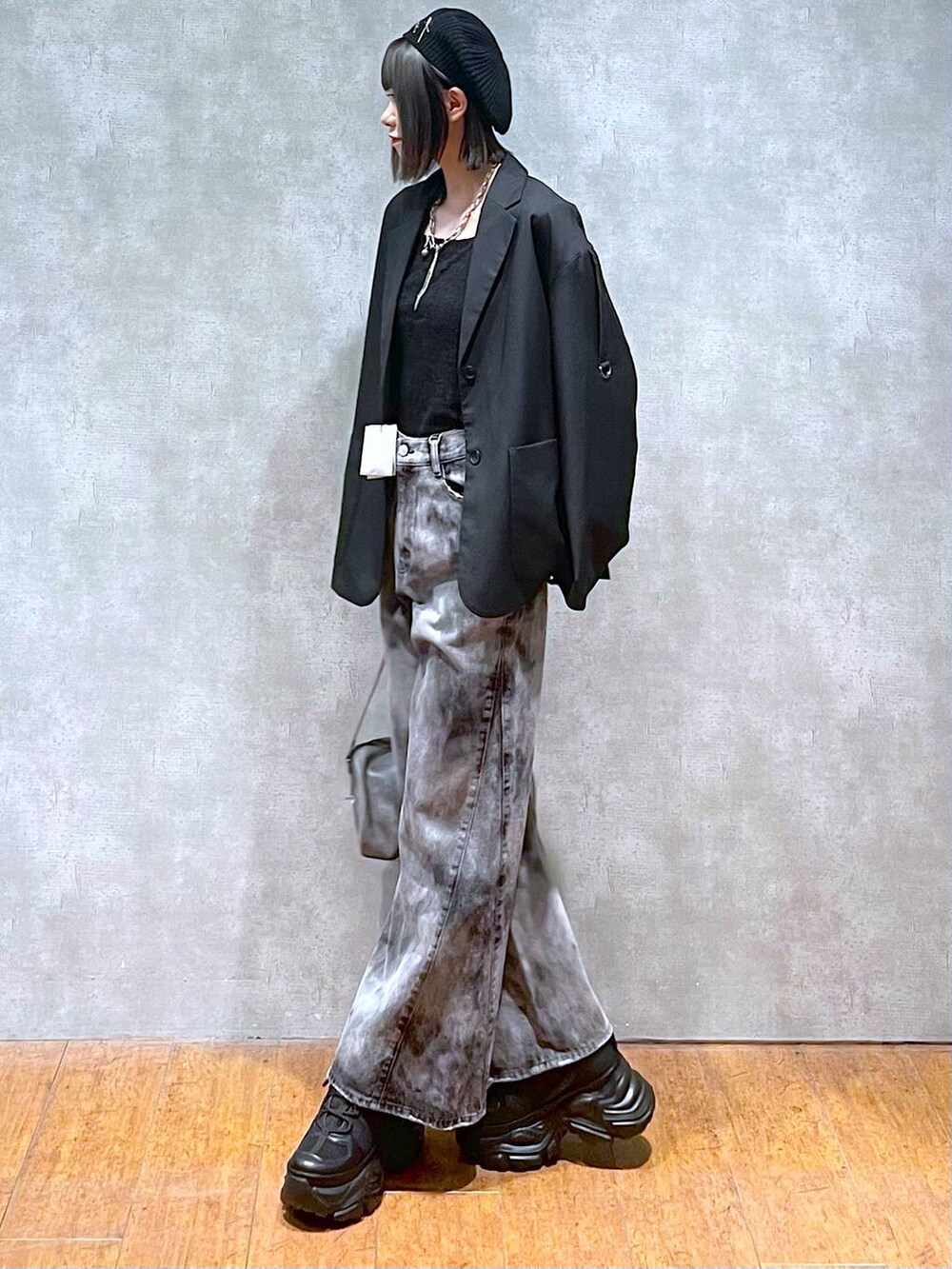 ブラック系のスニーカー、グレー系のショルダーバッグ、ブラック系のデニムパンツを着用したレディースの秋コーディネートの7枚目の写真