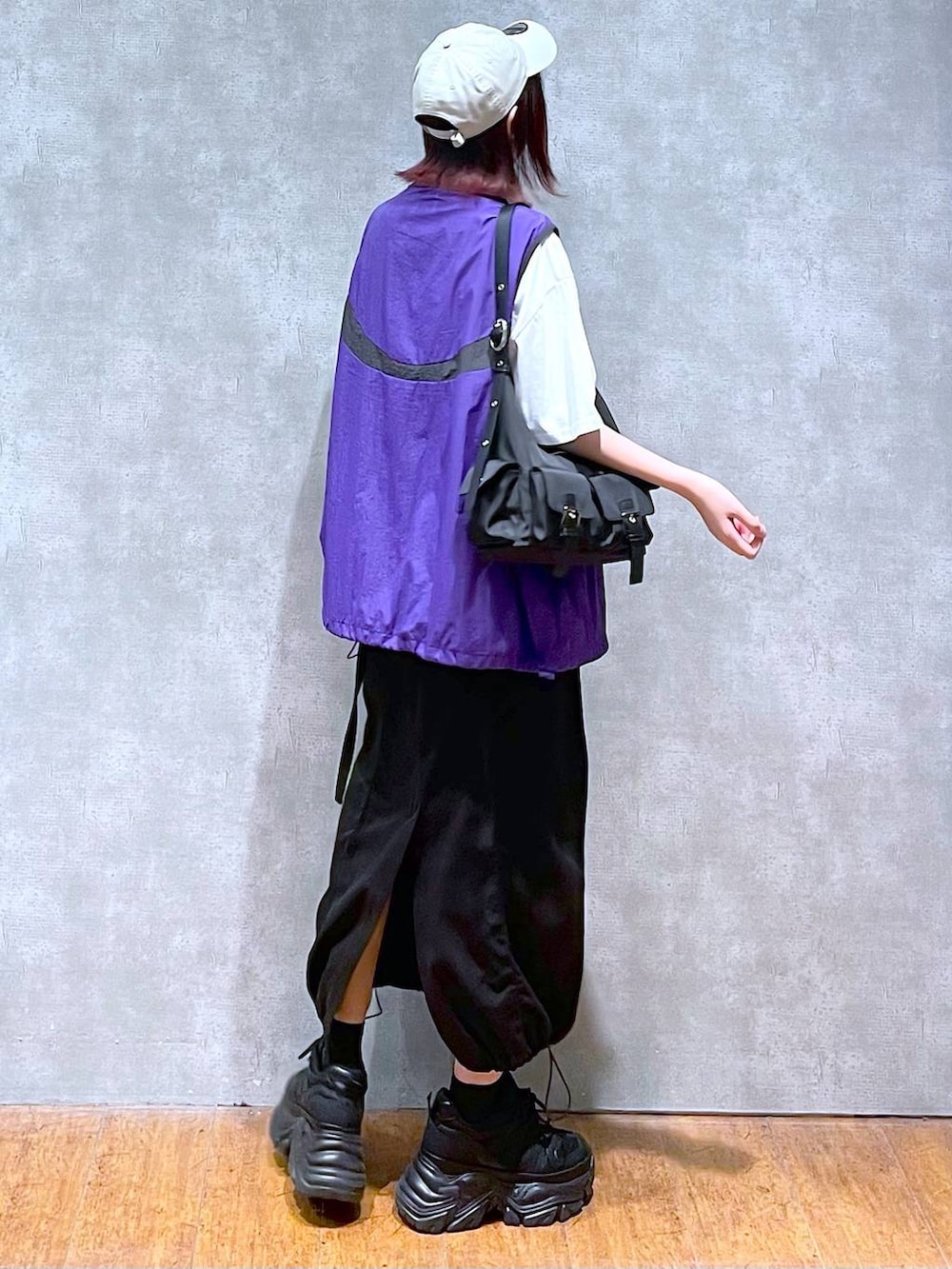 ブラック系のショルダーバッグ、ブラック系のスニーカー、パープル系のベストを着用したレディースの春コーディネートの5枚目の写真
