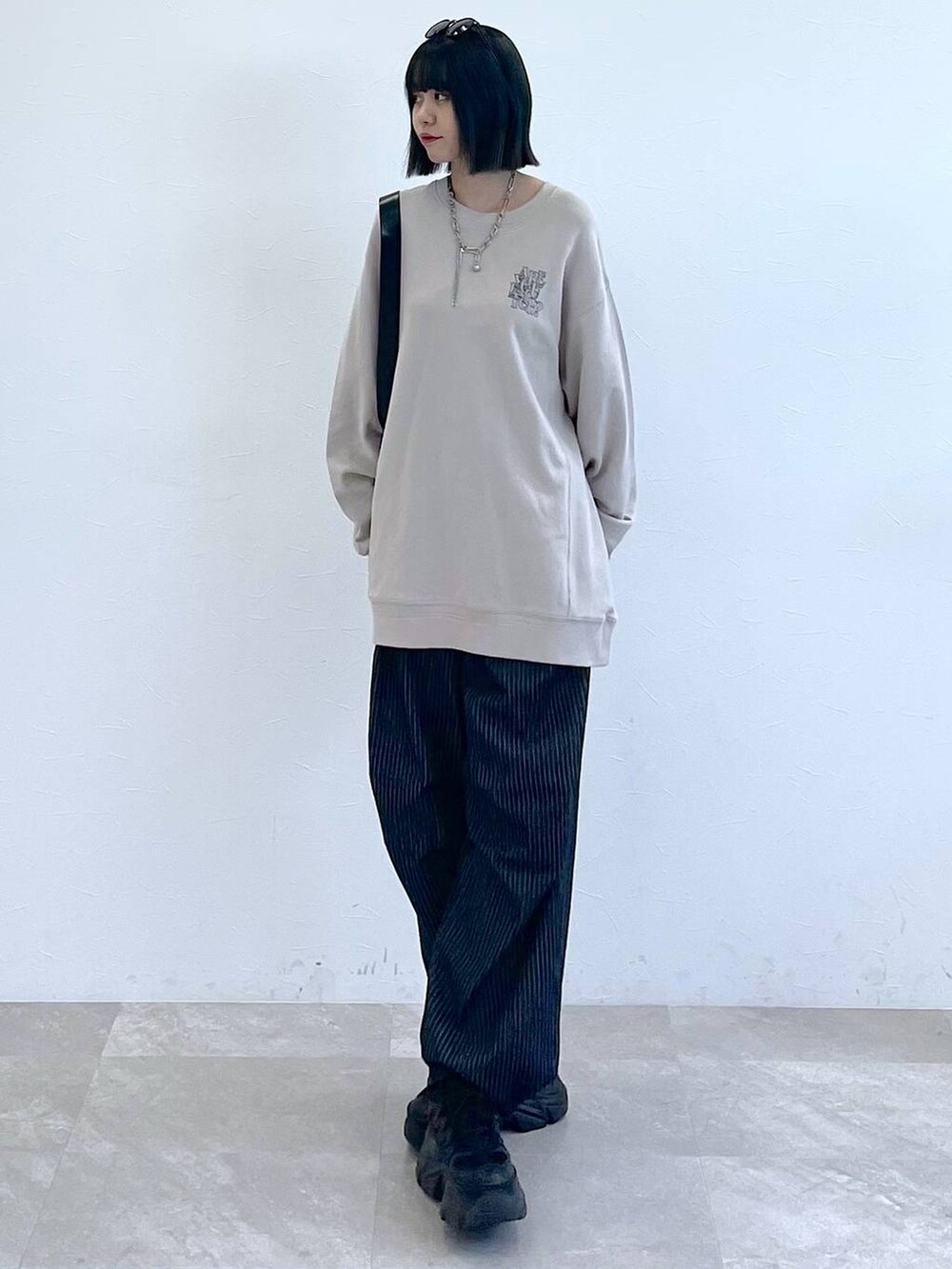 ブラック系のスニーカー、ブラック系のショルダーバッグ、ブラック系のデニムパンツを着用したレディースの秋コーディネートの5枚目の写真