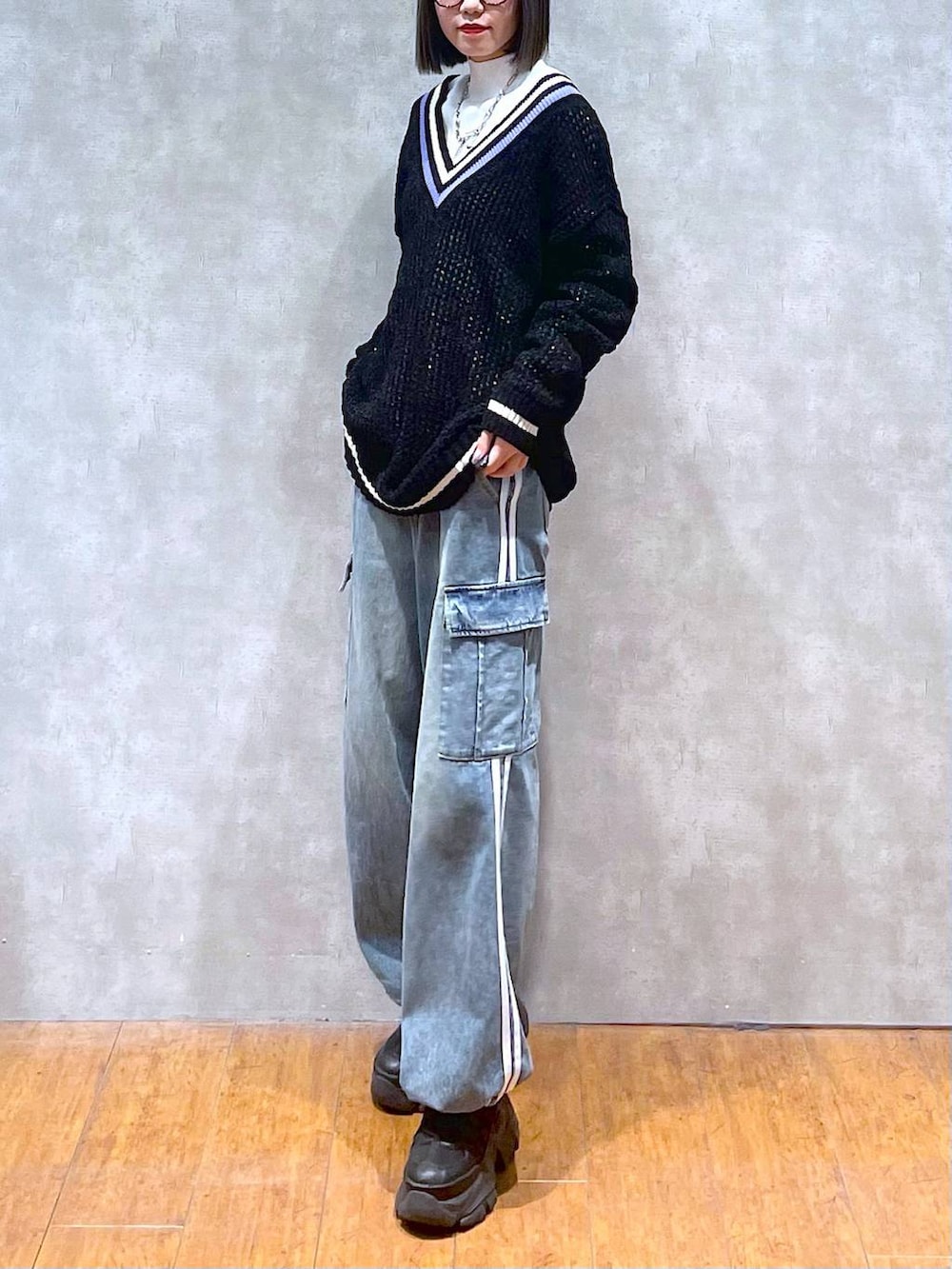 ブラック系のスニーカー、ブルー系のデニムパンツ、ブラック系のニット/セーターを着用したレディースの秋コーディネートの4枚目の写真