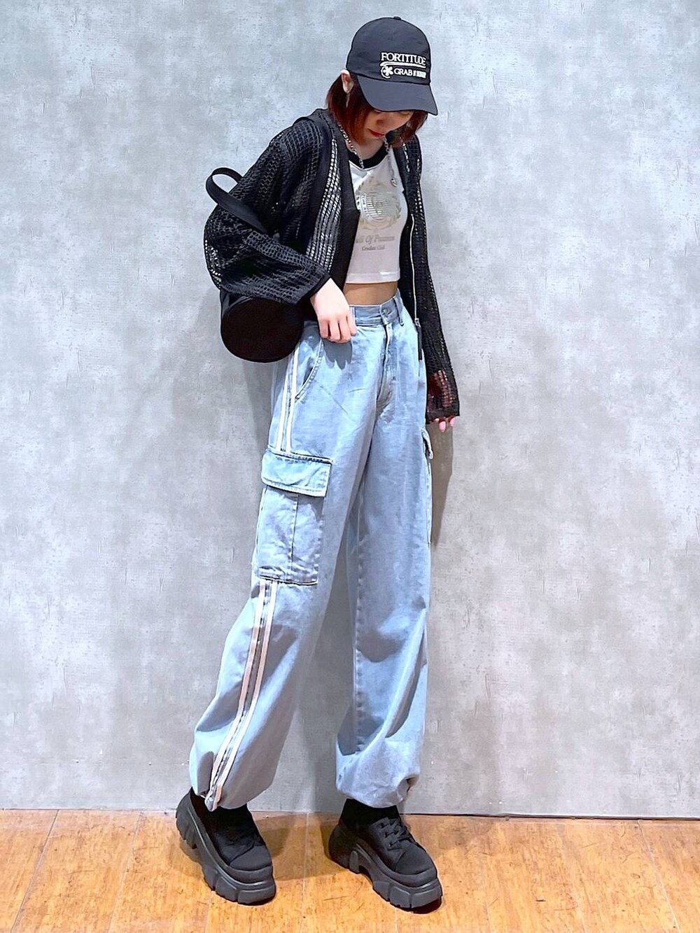 ブラック系のドラムバッグ、ホワイト系のTシャツ/カットソー、ブラック系のブーツを着用したレディースの春コーディネートの2枚目の写真