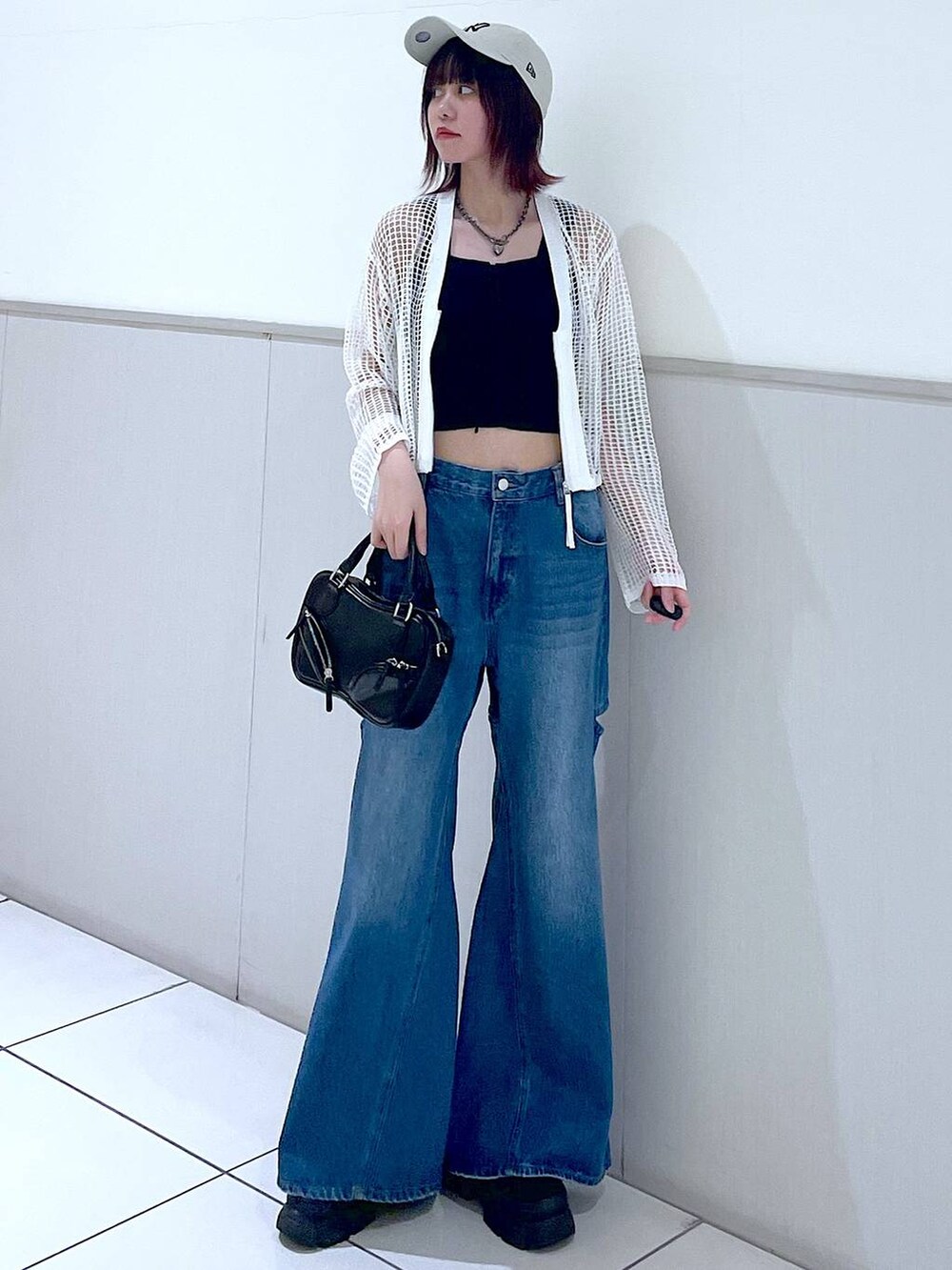 ホワイト系のカーディガン/ボレロ、ブラック系のタンクトップ、ブルー系のデニムパンツを着用したレディースの春コーディネートの3枚目の写真