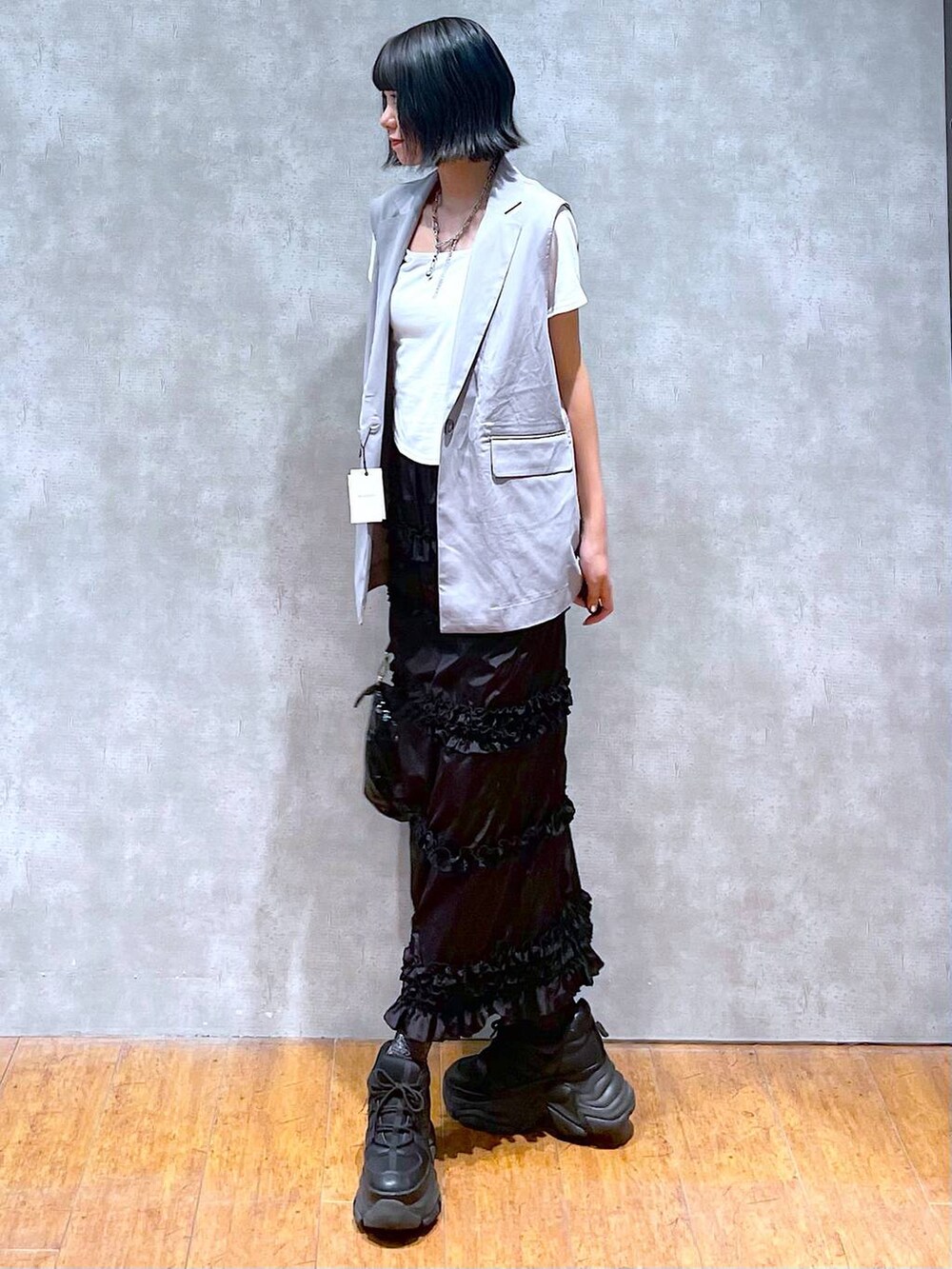 ブラック系のスニーカー、ホワイト系のTシャツ/カットソー、ブラック系のショルダーバッグを着用したレディースの夏コーディネートの2枚目の写真