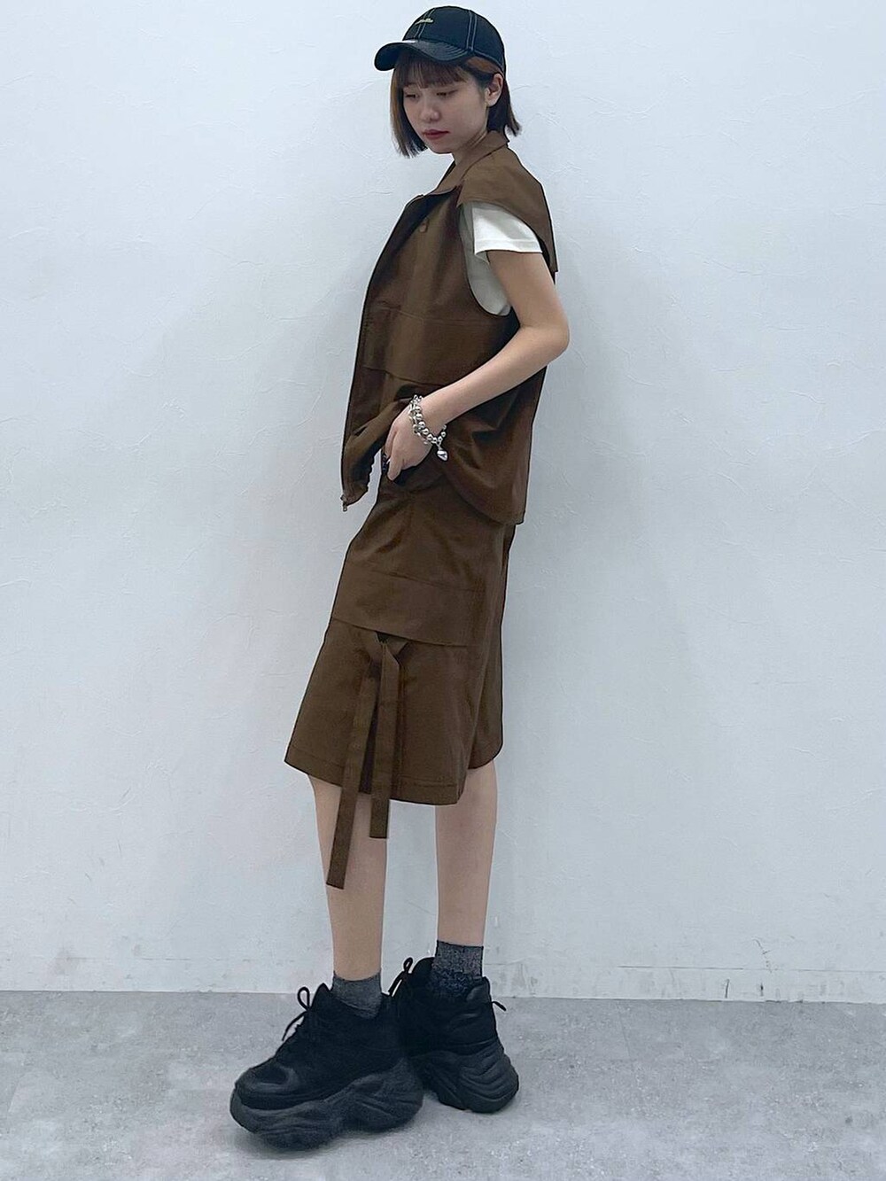 ブラック系のスニーカー、ベージュ系のTシャツ/カットソー、ブラウン系のベストを着用したレディースの夏コーディネートの4枚目の写真