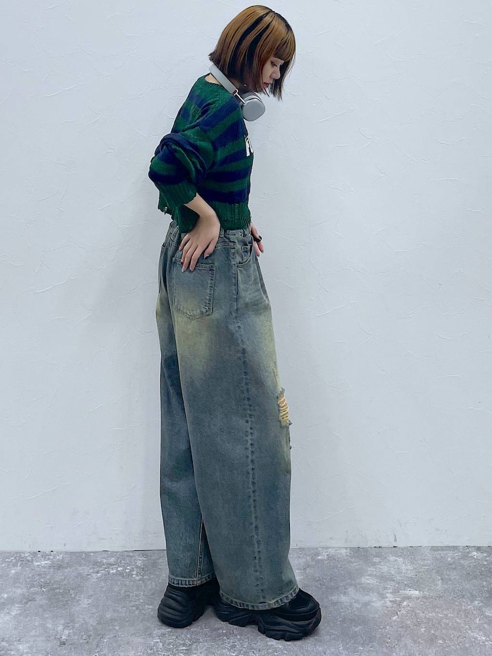 ブラック系のスニーカー、ブルー系のデニムパンツ、グリーン系のニット/セーターを着用したレディースの秋コーディネートの3枚目の写真