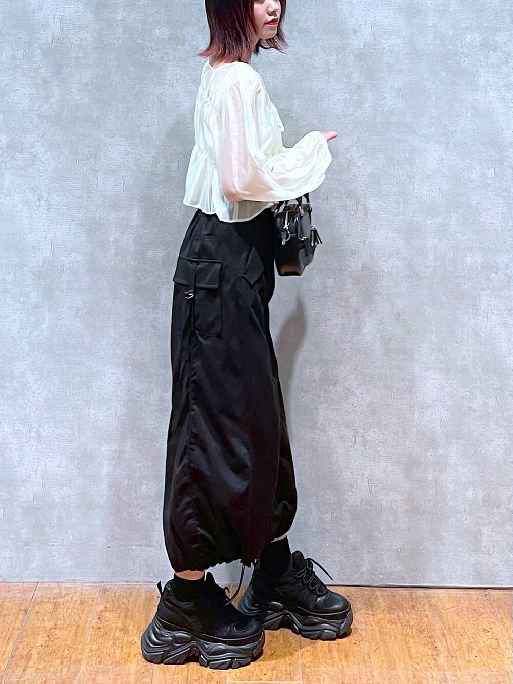 ブラック系のスニーカー、ベージュ系のシャツ/ブラウス、ホワイト系のキャミソールを着用したレディースの春コーディネートの2枚目の写真