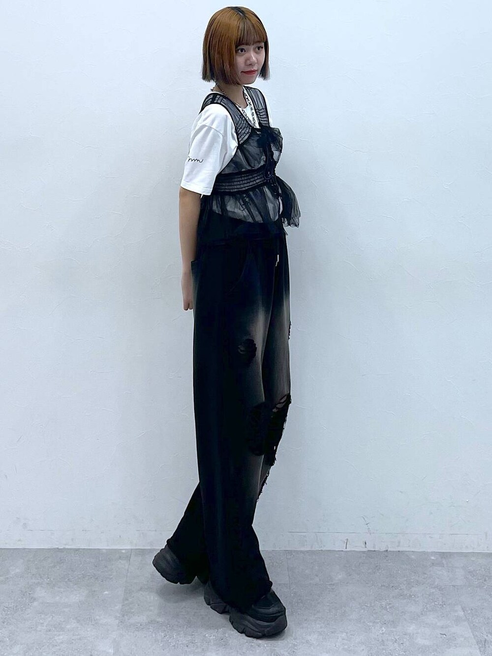 ブラック系のスニーカー、ブラック系のベスト、ホワイト系のTシャツ/カットソーを着用したレディースの夏コーディネートの5枚目の写真