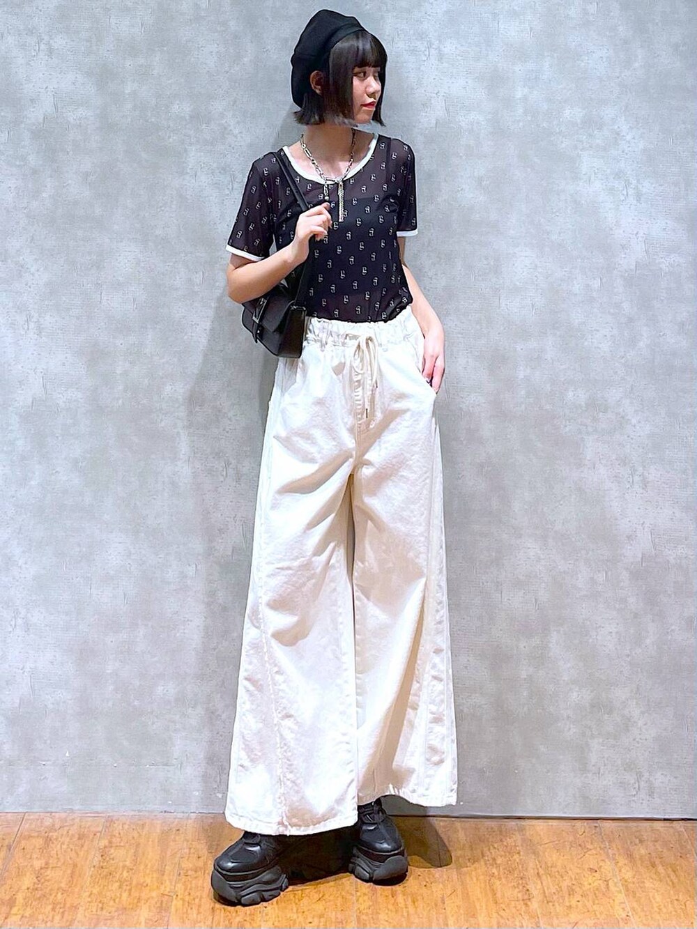 ブラック系のスニーカー、ブラック系のキャミソール、ホワイト系のデニムパンツを着用したレディースの夏コーディネートの6枚目の写真