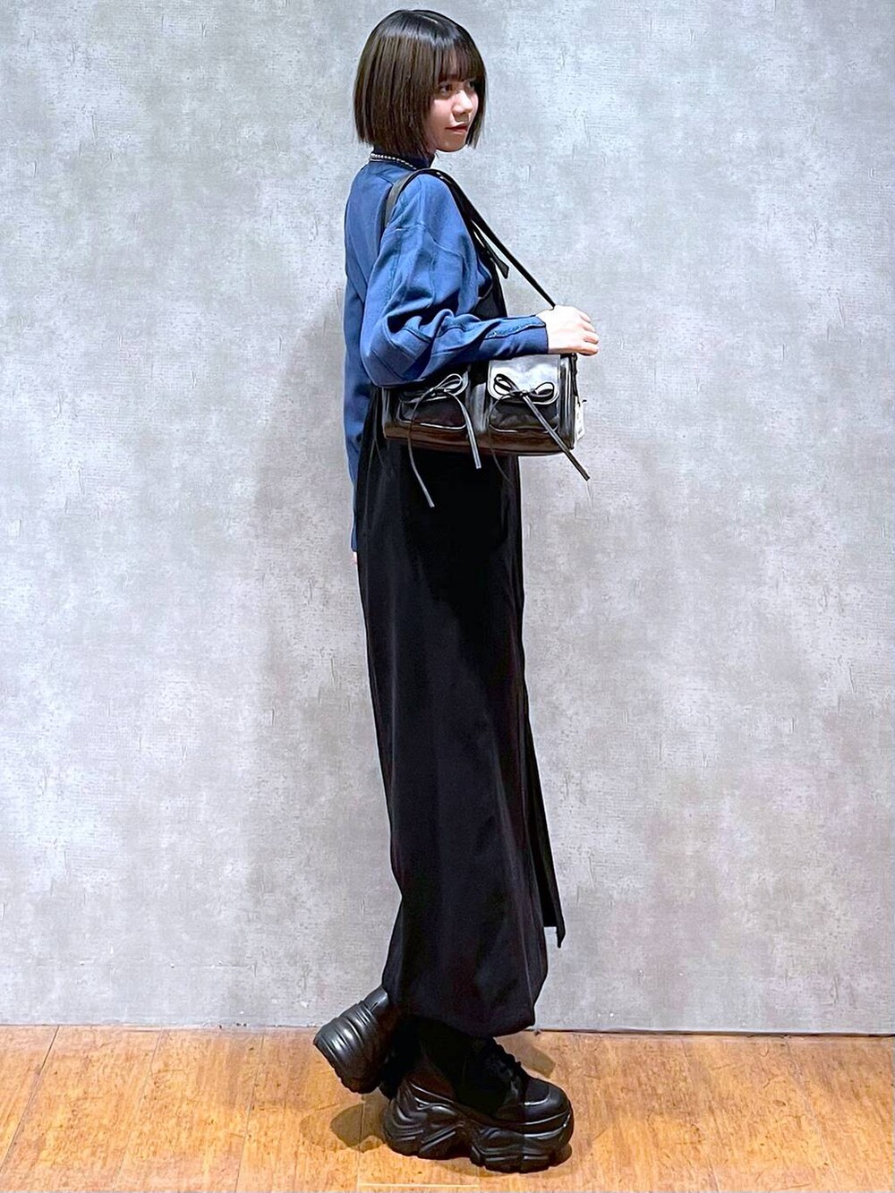 ブラック系のショルダーバッグ、ブラック系のブーツ、ブルー系のニット/セーターを着用したレディースの秋コーディネートの4枚目の写真