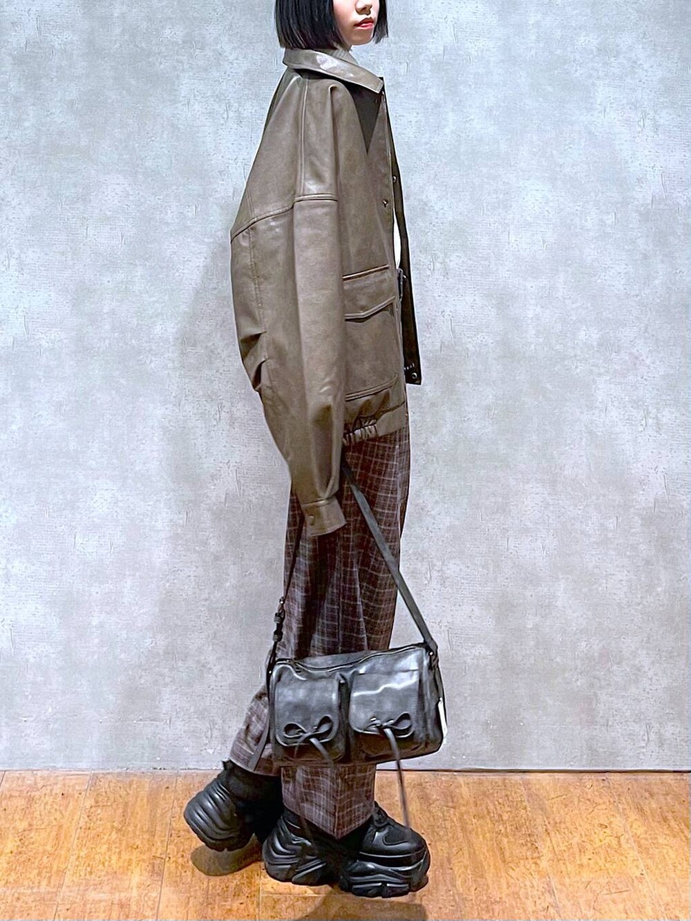 ブラック系のスニーカー、ブラック系のショルダーバッグ、ブラウン系のブルゾンを着用したレディースの秋コーディネートの4枚目の写真