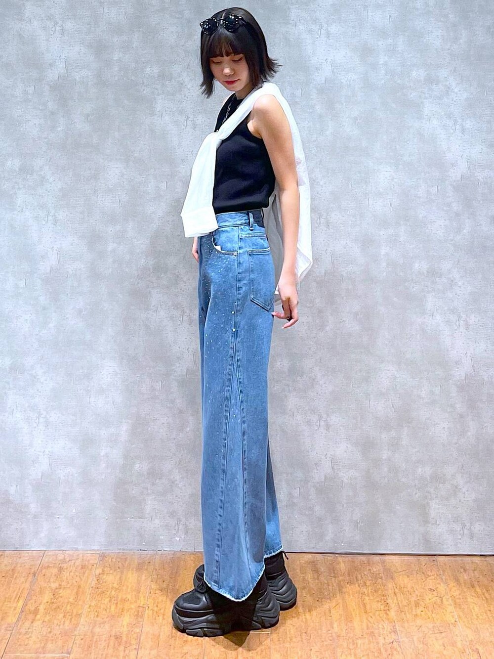ブラック系のスニーカー、ブラック系のタンクトップ、ブルー系のデニムパンツを着用したレディースの夏コーディネートの7枚目の写真