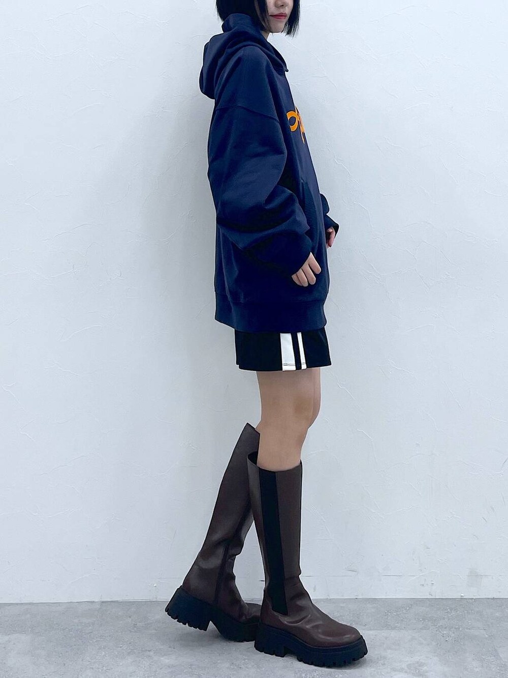 ブルー系のパーカー、ブラウン系のブーツ、ブラック系のスカートを着用したレディースの冬コーディネートの2枚目の写真