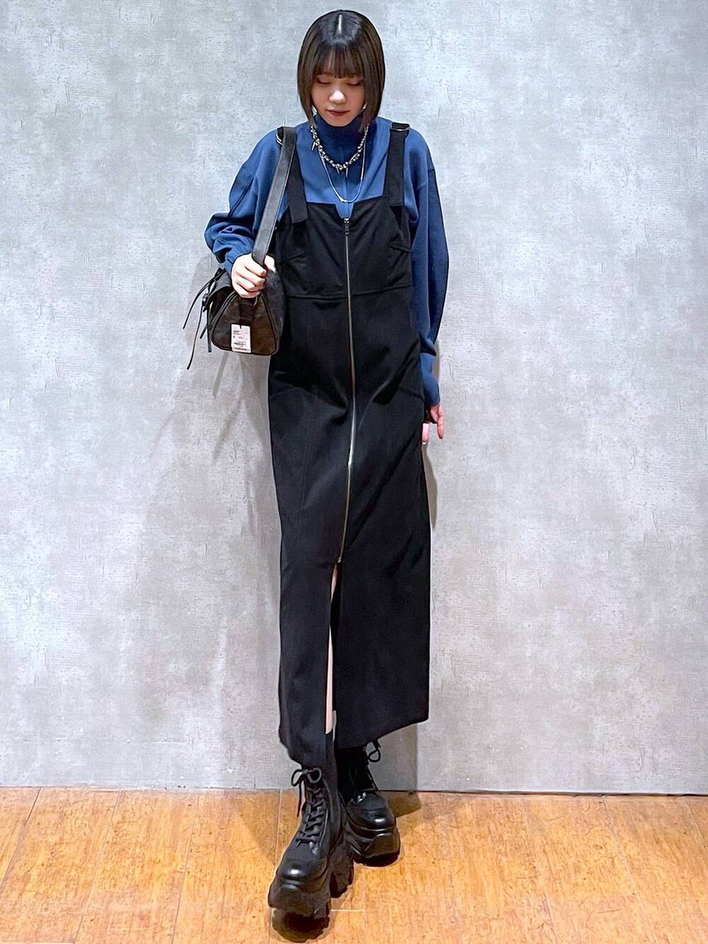 ブラック系のショルダーバッグ、ブラック系のブーツ、ブルー系のニット/セーターを着用したレディースの秋コーディネートの5枚目の写真