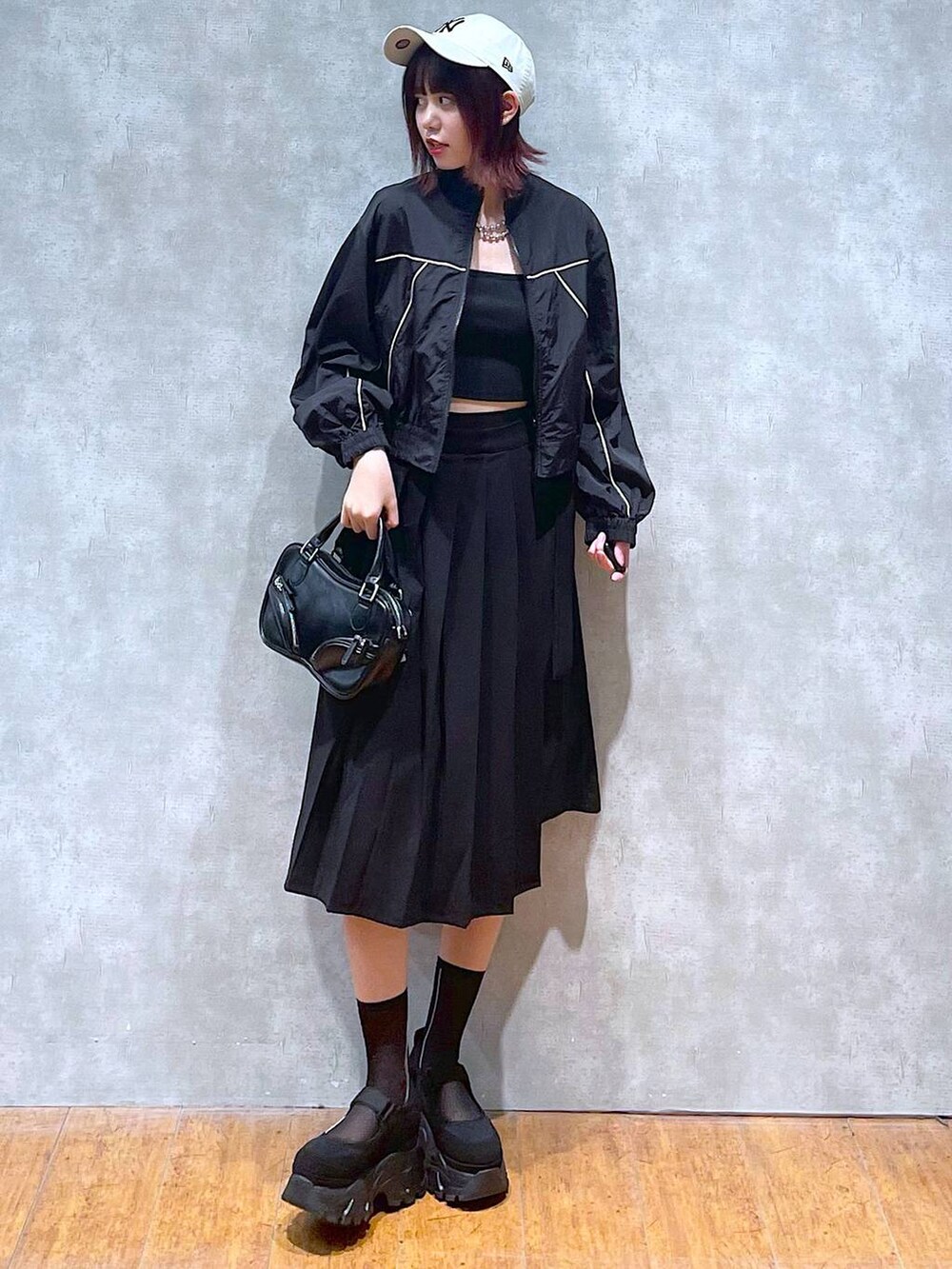 ブラック系のブルゾン、ブラック系のスカート、ブラック系のキャミソールを着用したレディースの春コーディネートの2枚目の写真