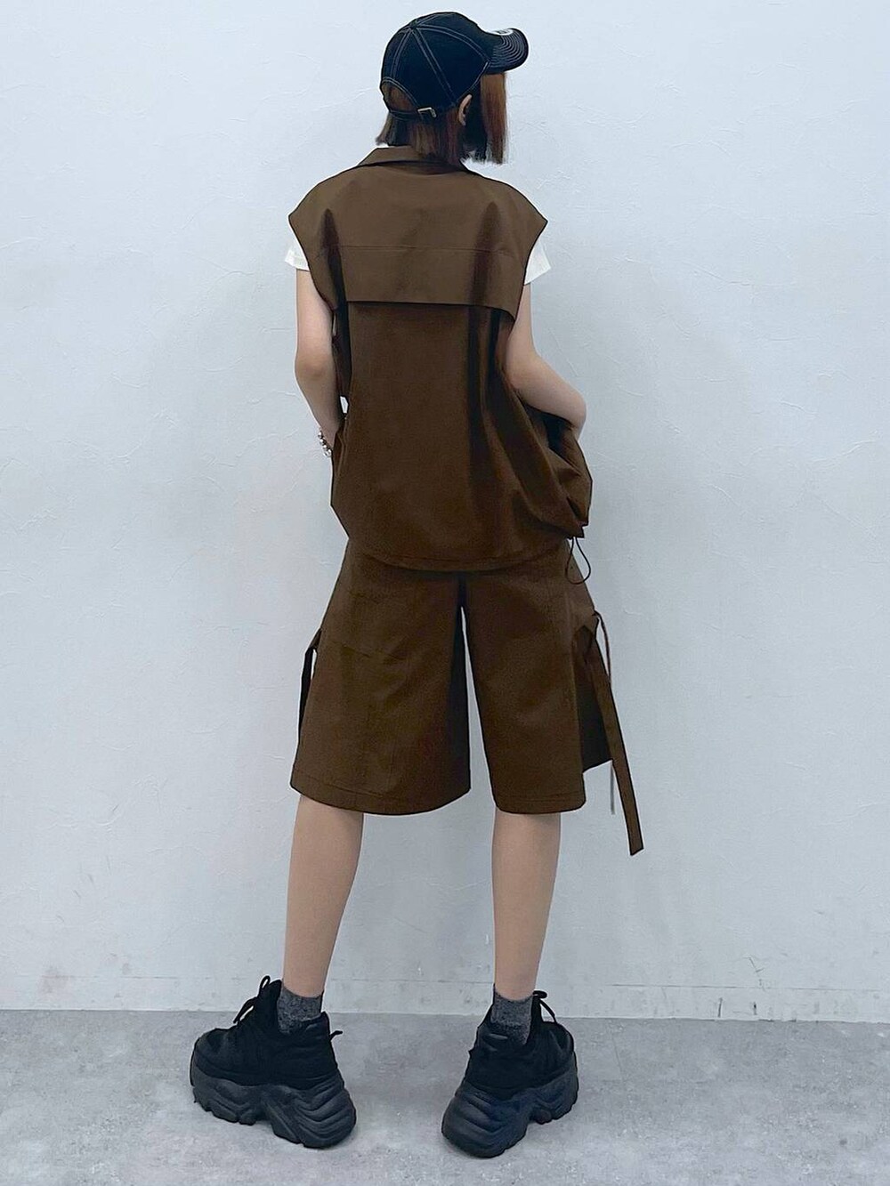 ブラック系のスニーカー、ベージュ系のTシャツ/カットソー、ブラウン系のベストを着用したレディースの夏コーディネートの3枚目の写真