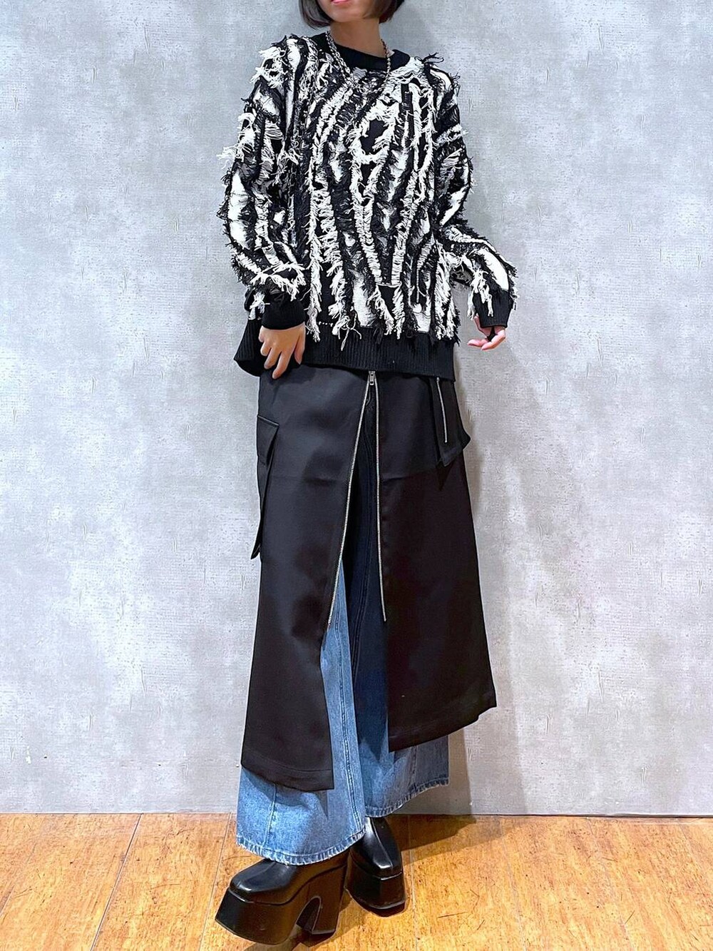 ブラック系のスカート、ブルー系のデニムパンツ、ブラック系のブーツを着用したレディースの冬コーディネートの3枚目の写真