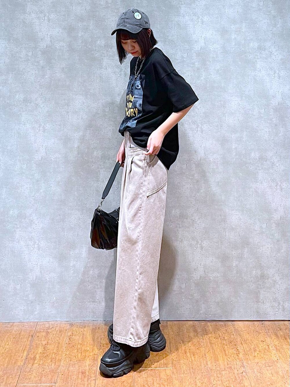 ブラック系のスニーカー、ブラック系のショルダーバッグ、ベージュ系のデニムパンツを着用したレディースの夏コーディネートの5枚目の写真