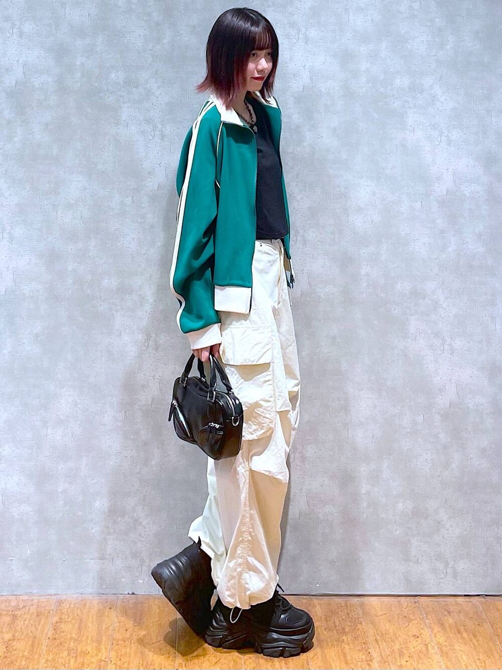 グリーン系のセットアップ、ブラック系のボストンバッグ、ホワイト系のカーゴパンツを着用したレディースの春コーディネートの6枚目の写真